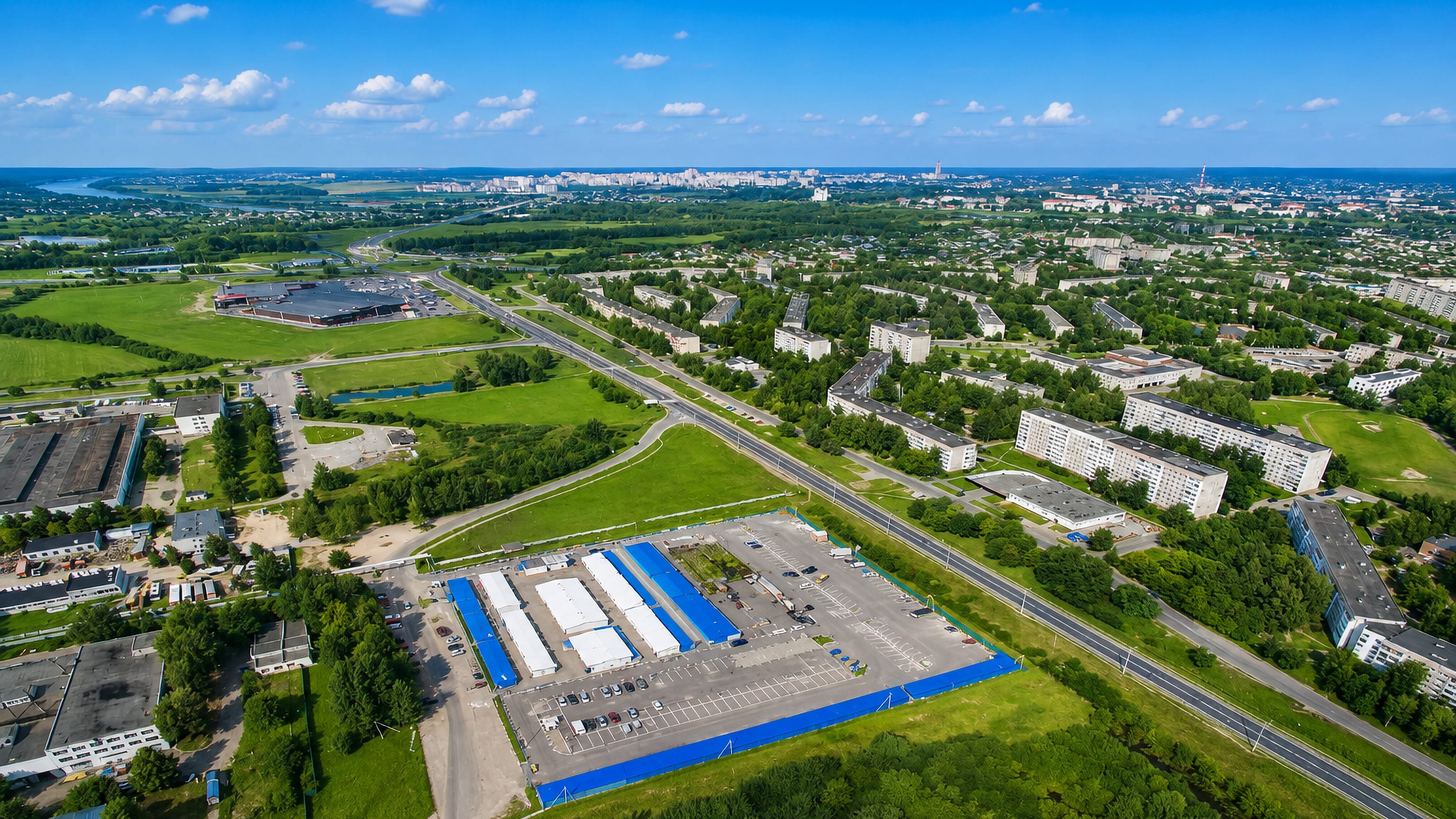 Aerial view over Polotsk, Belarus, showing Soviet-era apartment blocks, a retail park and surrounding green fields.
