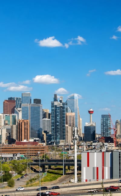 Calgary's downtown skyline and Calgary Tower rising beyond a highway and storage building near Bowness.
