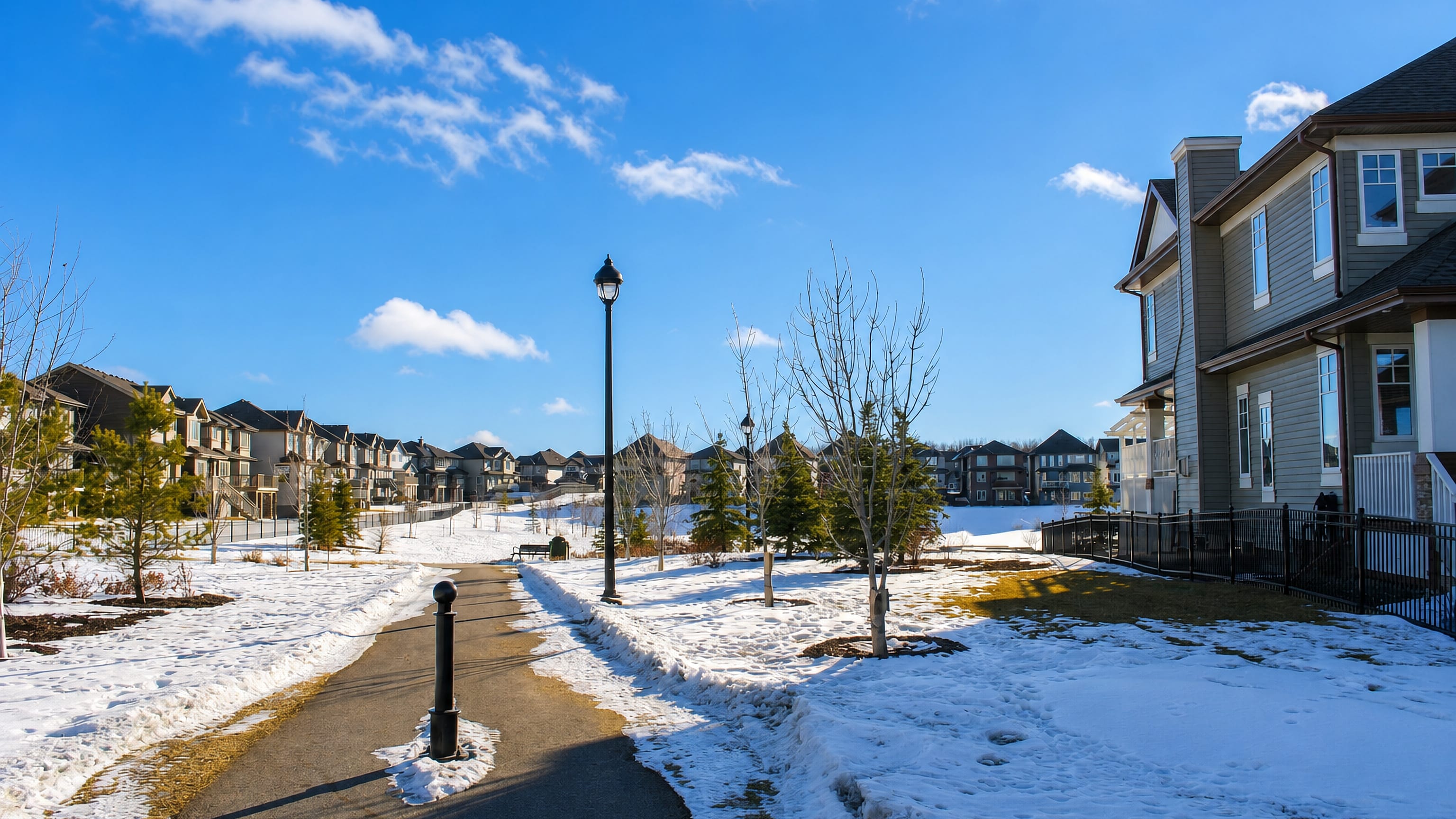 Snow-lined path between new suburban houses under a clear sky in Ambleside, Edmonton.