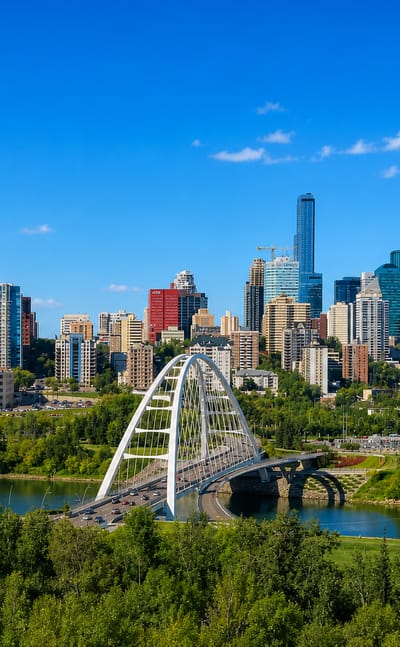Edmonton's downtown skyline behind the white Walterdale Bridge arch over the North Saskatchewan River.