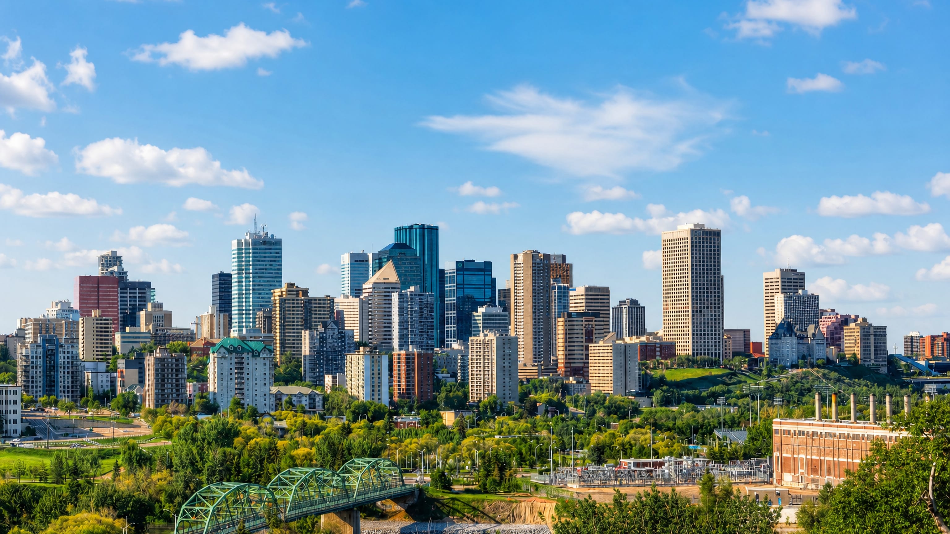 Edmonton's downtown skyline above the North Saskatchewan River valley with a green truss bridge in front