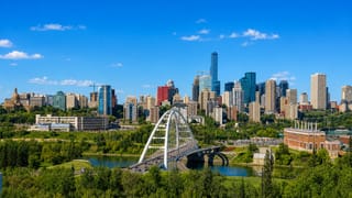 Edmonton's downtown skyline behind the white Walterdale Bridge arch over the North Saskatchewan River.