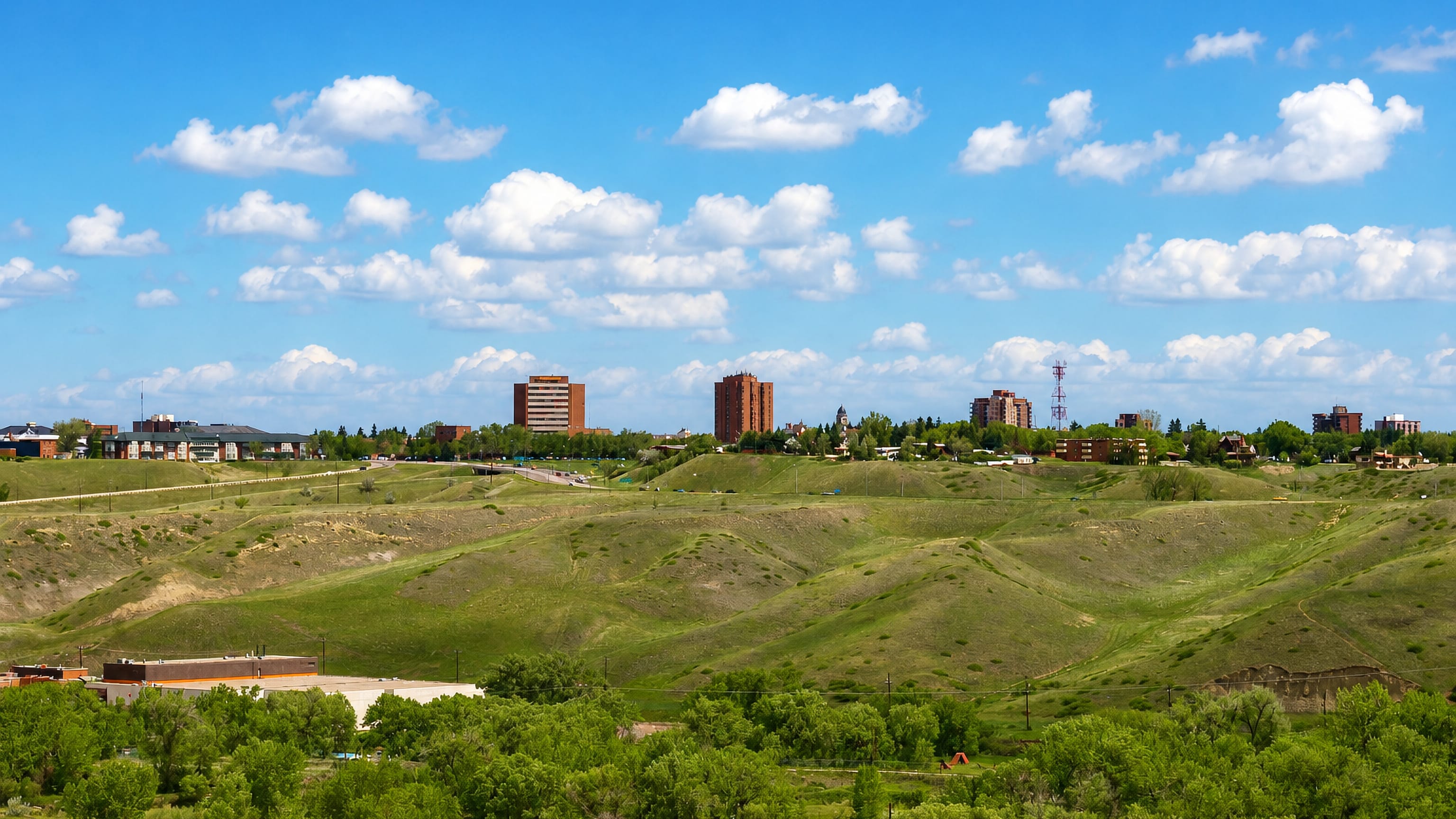 Lethbridge's low skyline above the grassy coulees of the Oldman River valley in southern Alberta.