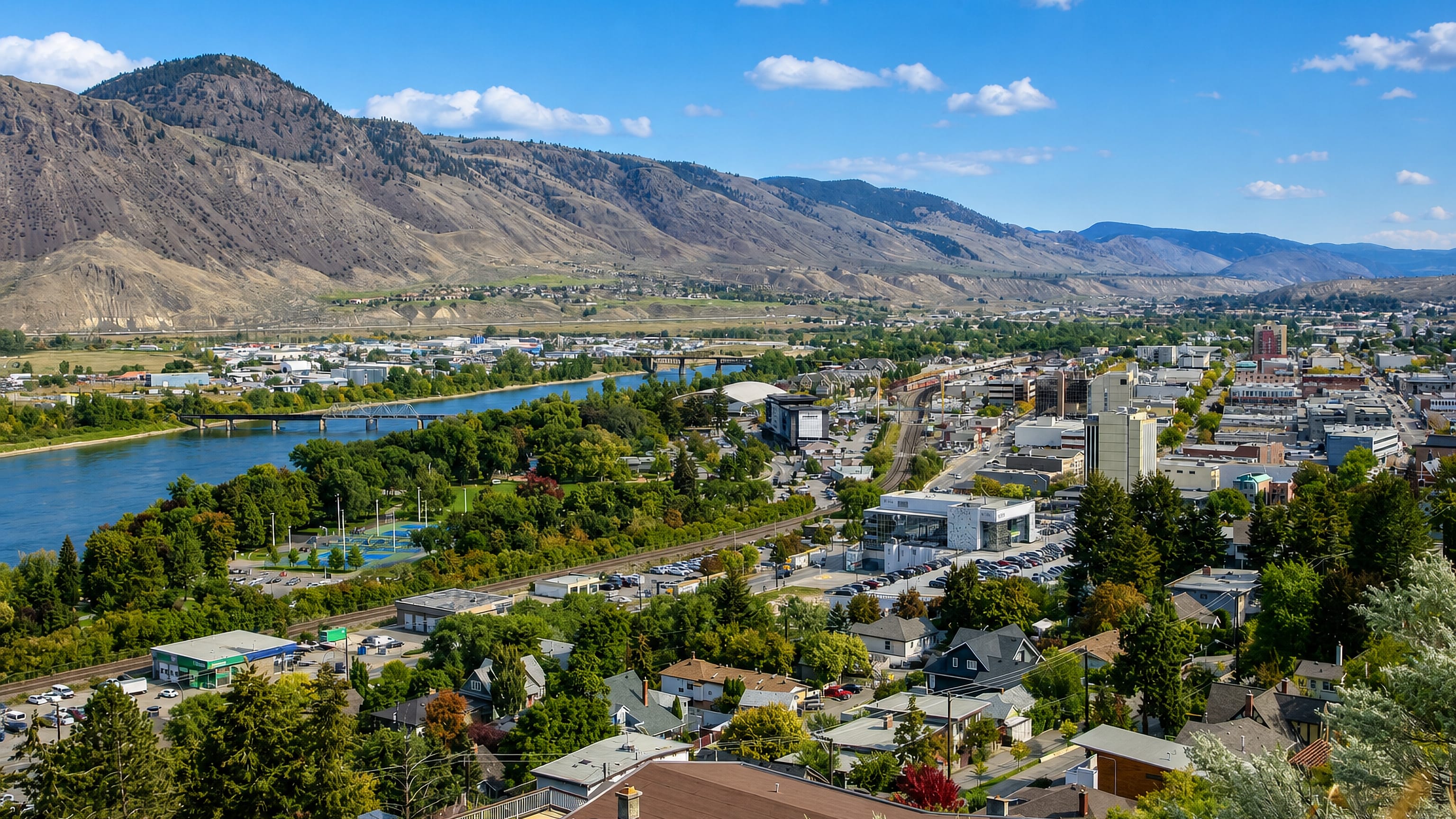 Kamloops, British Columbia, spread along the Thompson River below dry brown hills, with its downtown and bridges.