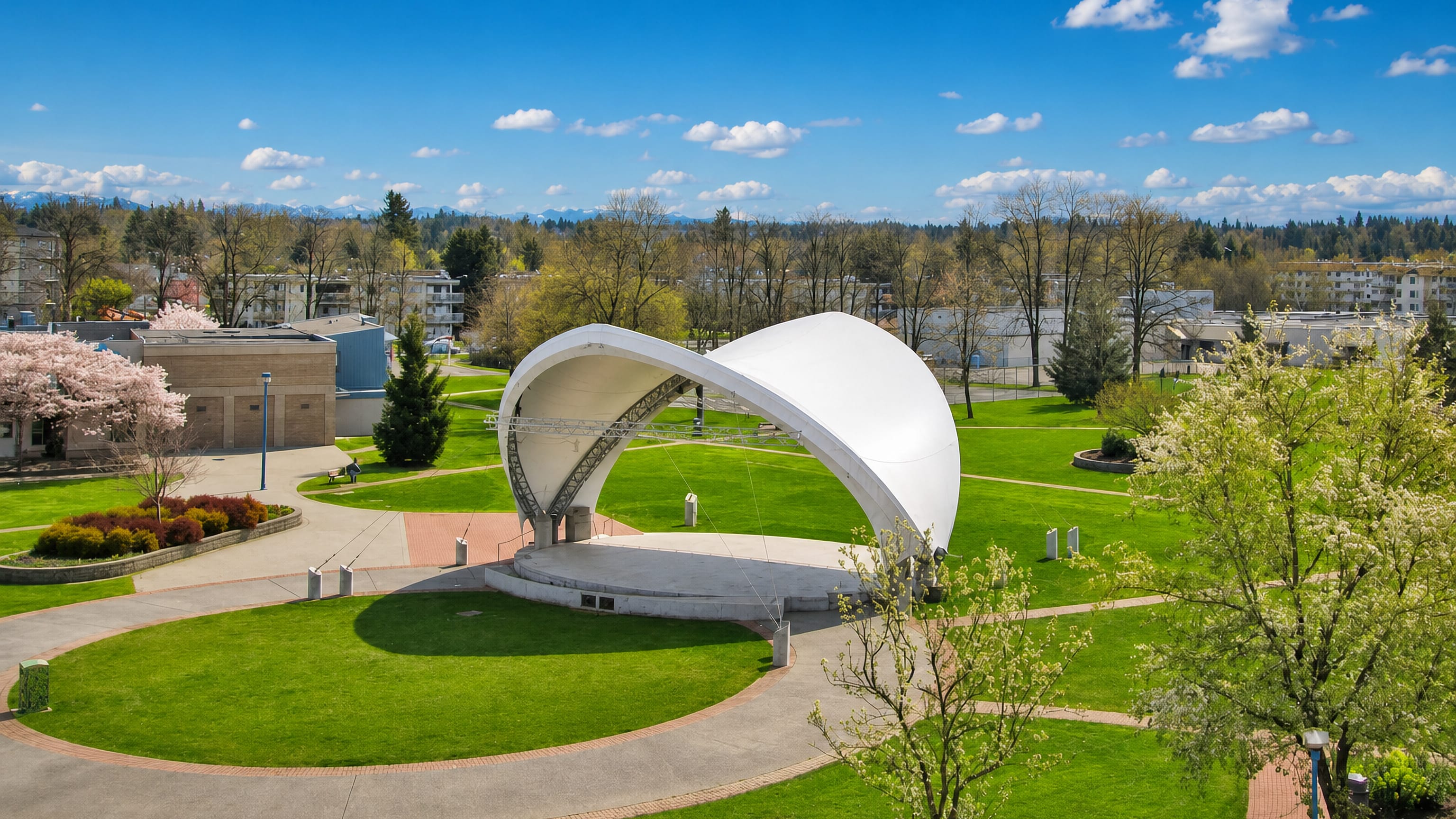 Douglas Park band shell in Langley, British Columbia, framed by spring blossoms and low-rise apartments.