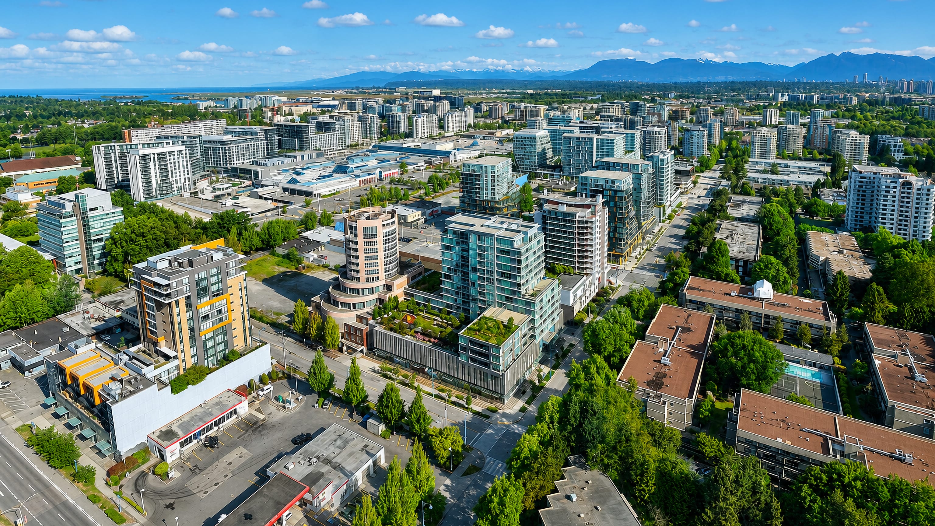Aerial view of Richmond, British Columbia, with condo towers, flat delta and the Coast Mountains beyond.