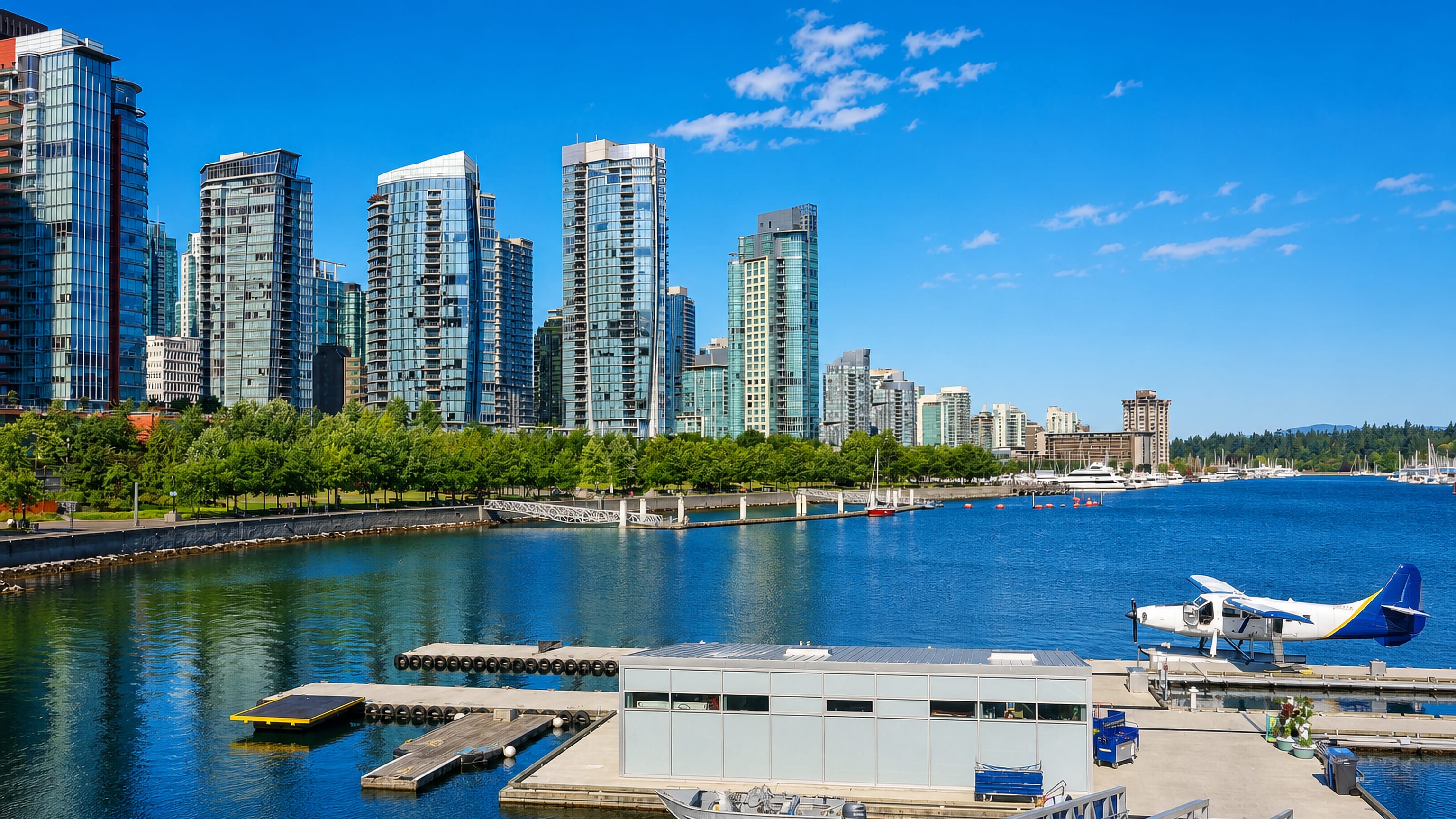 Glass towers, marina and a docked seaplane along the waterfront of Coal Harbour in Vancouver.