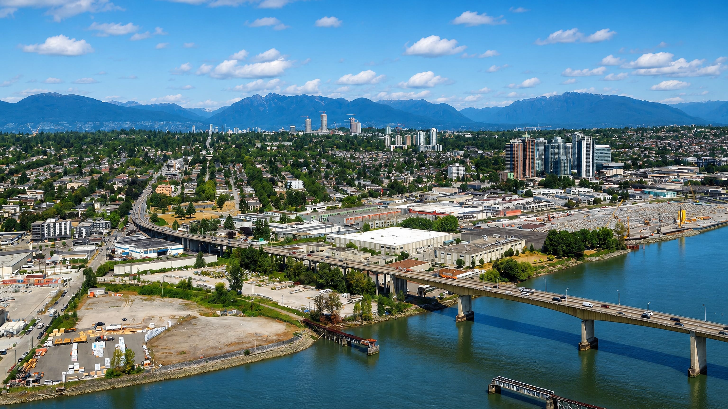 Marpole's Fraser River waterfront in Vancouver, with a bridge crossing and the North Shore mountains behind