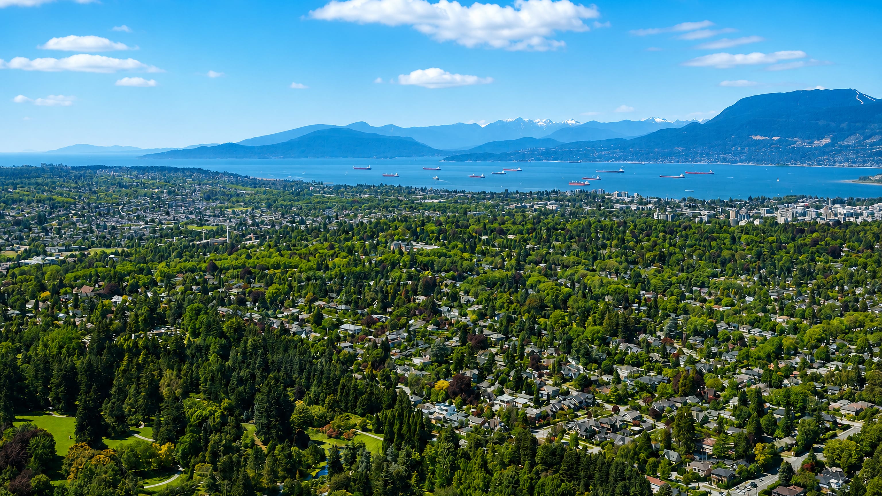 Aerial view over Shaughnessy's leafy streets and homes in Vancouver, with English Bay and the North Shore mountains