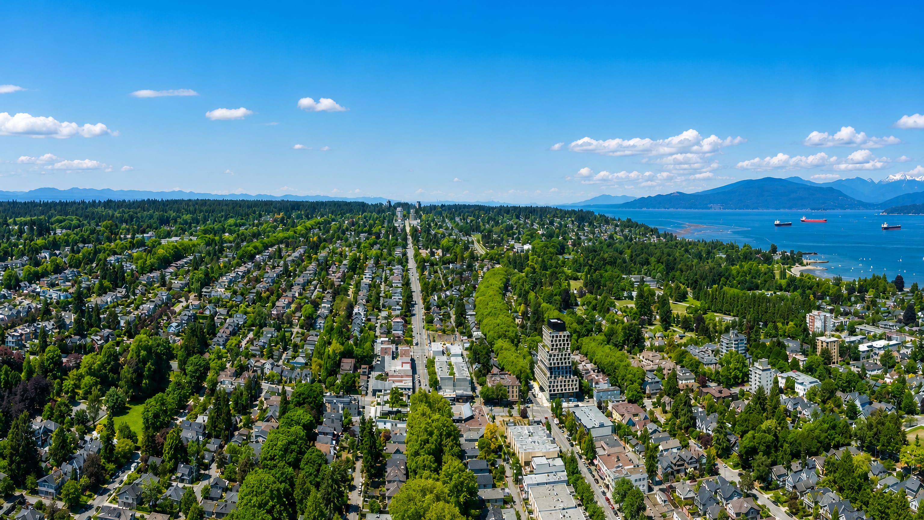 Aerial view of leafy West Point Grey, Vancouver, looking over English Bay to the North Shore mountains.