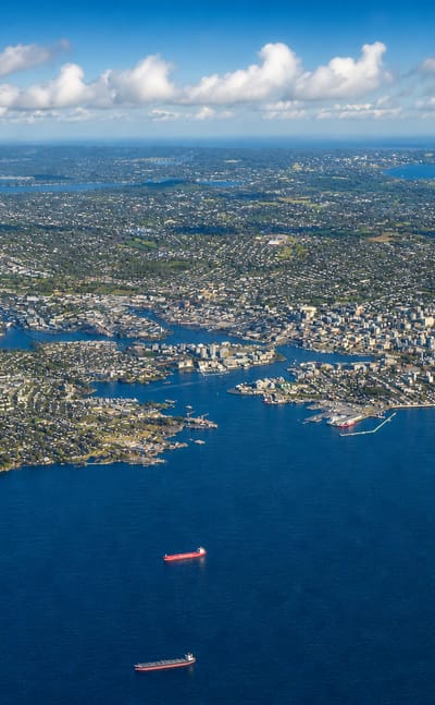 High aerial view of the coastal city of Victoria on its peninsula with ships offshore, British Columbia