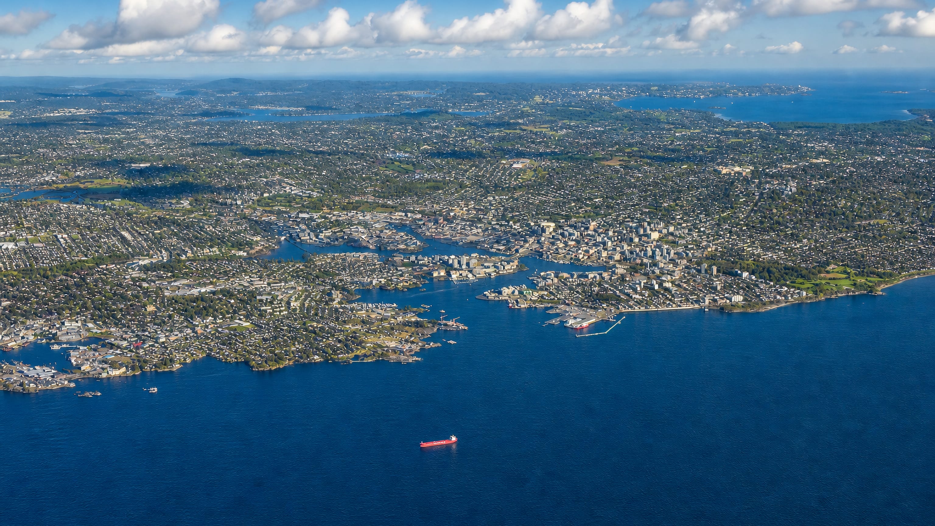 High aerial view of the coastal city of Victoria on its peninsula with ships offshore, British Columbia