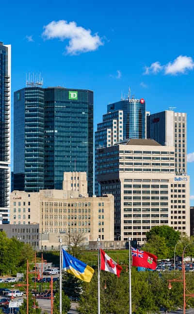 Downtown Winnipeg skyline with the TD, BMO and Richardson towers above flags on Portage Avenue.