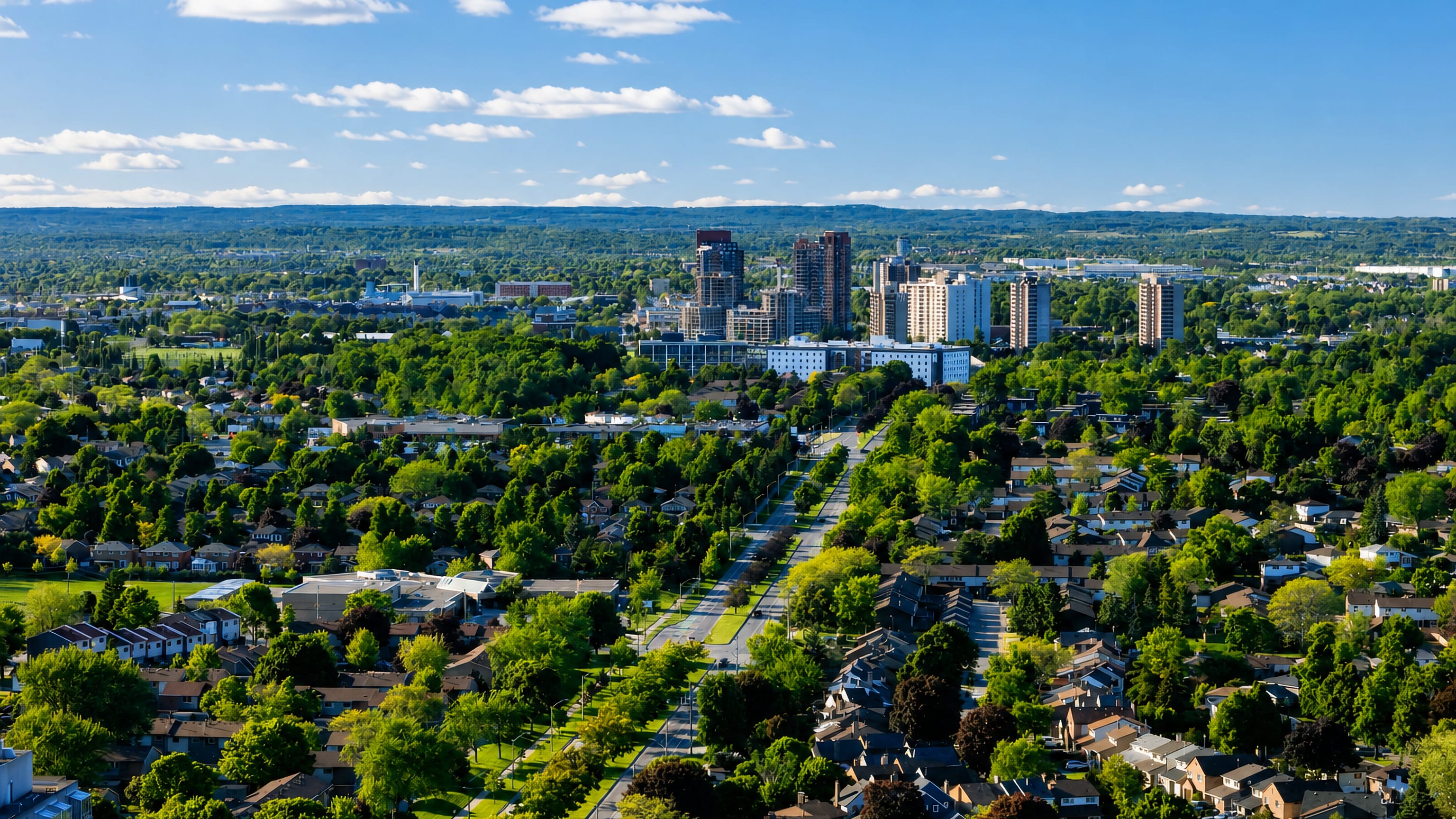 Leafy residential streets of Ajax, Ontario, running toward a cluster of mid-rise towers on the horizon.