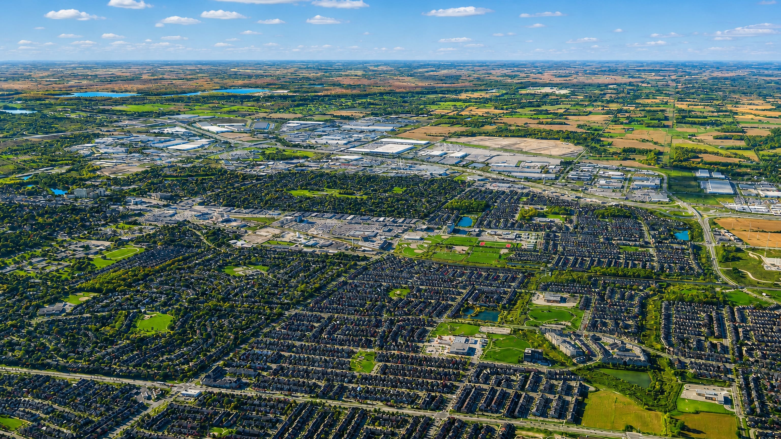 Aerial view over Milton, Ontario, showing suburban housing grids, industrial parks and surrounding farmland.