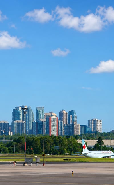 Mississauga's City Centre skyline with the twisting Absolute towers rising beyond an airport apron with jets.