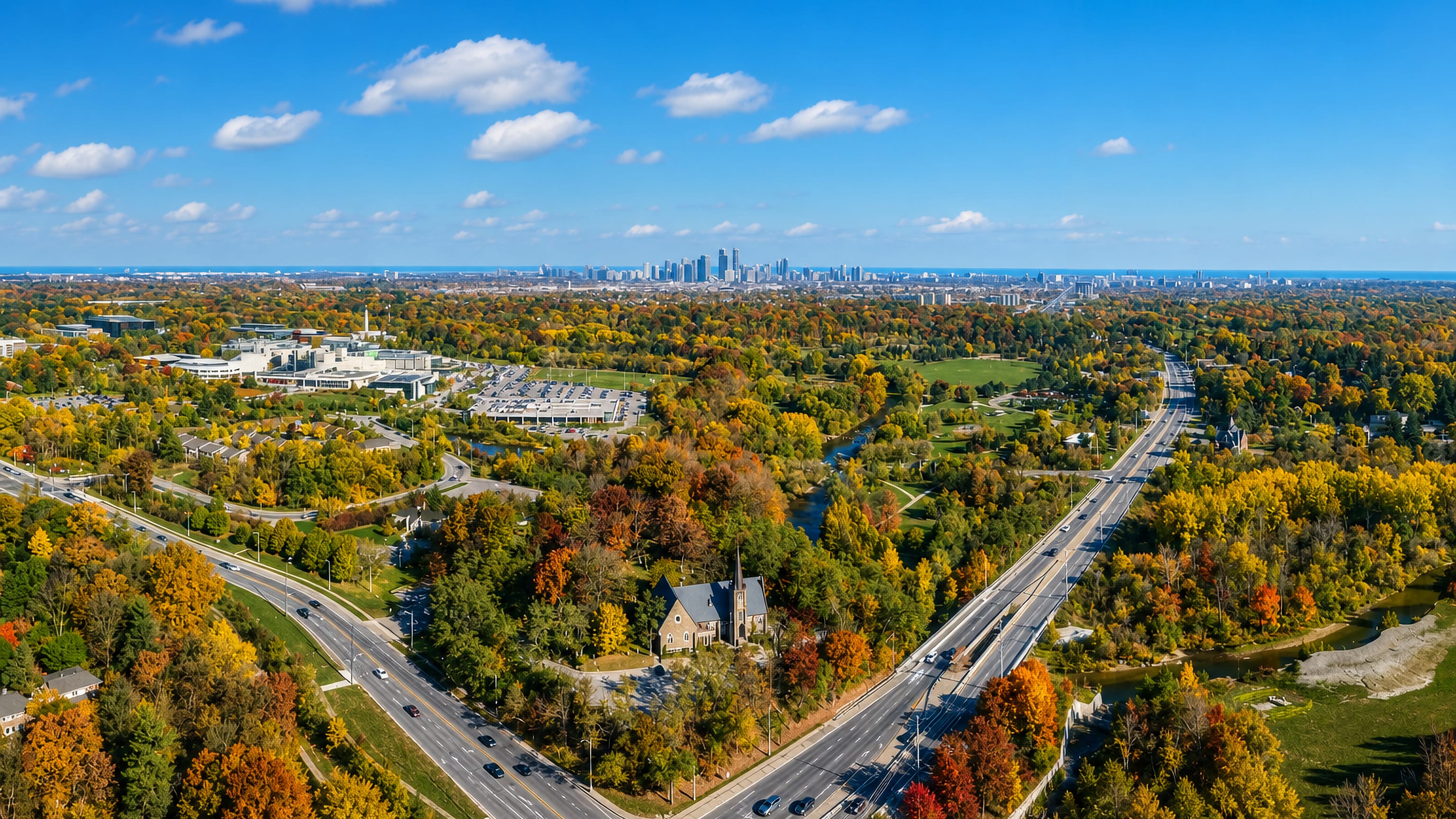 Autumn aerial of Erindale, Mississauga, with the Credit River, a stone church and Toronto's skyline beyond.