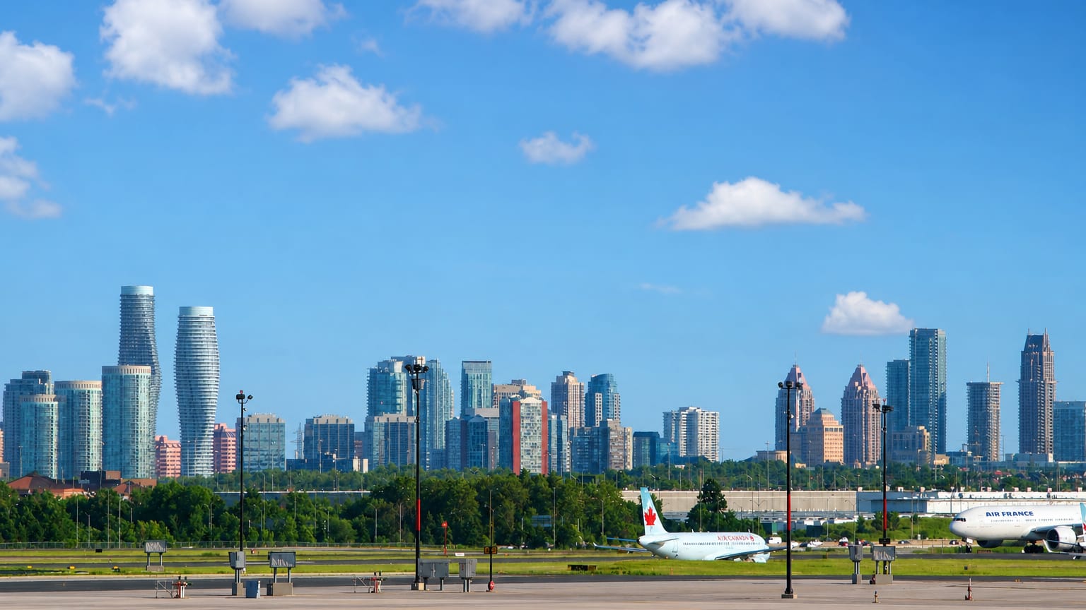 Mississauga's City Centre skyline with the twisting Absolute towers rising beyond an airport apron with jets.