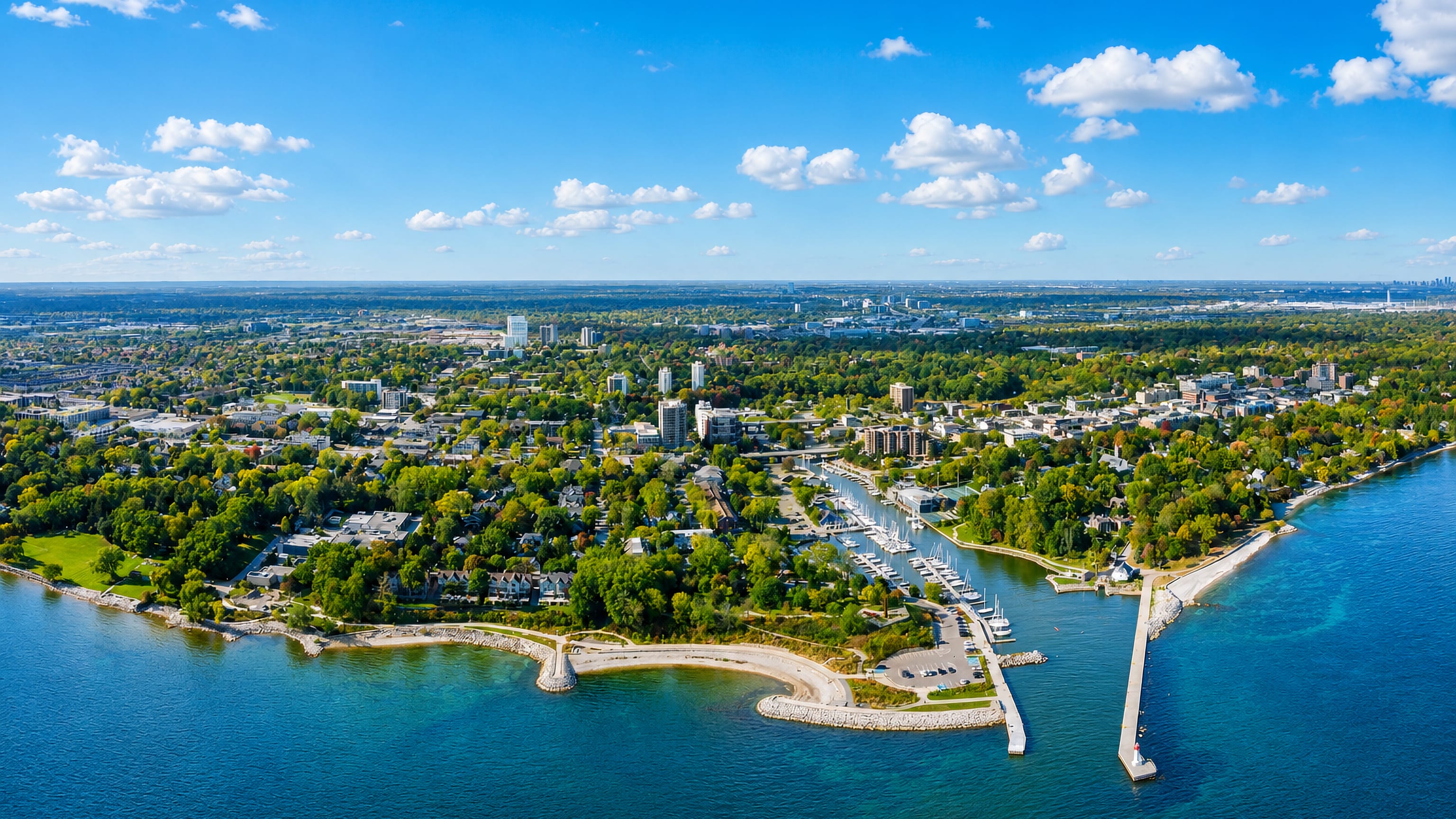 Aerial view of Oakville, Ontario, its harbour piers and marina meeting Lake Ontario amid leafy streets.