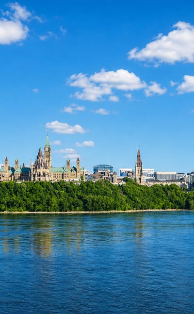Ottawa's Parliament Hill with the Peace Tower and Château Laurier seen across the Ottawa River on a sunny day.