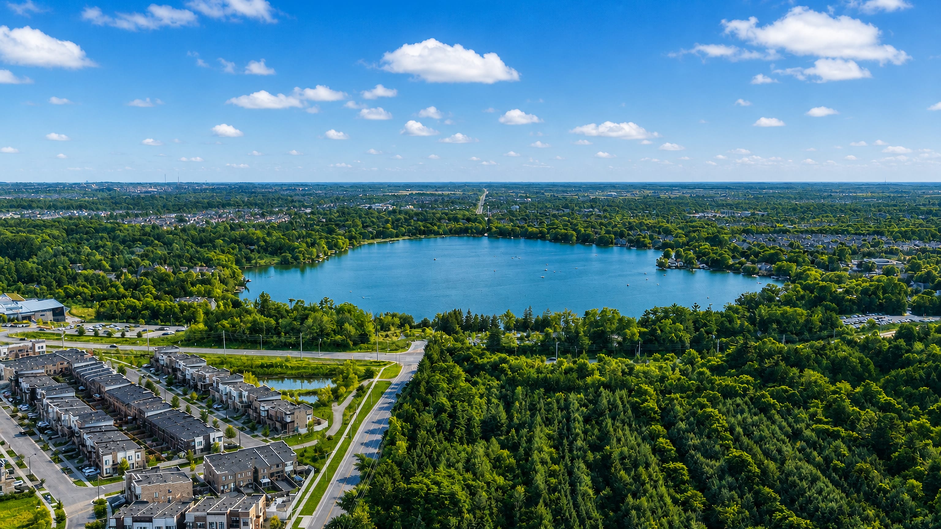 Aerial view of Richmond Hill, Ontario, with Lake Wilcox ringed by forest and modern townhouses.