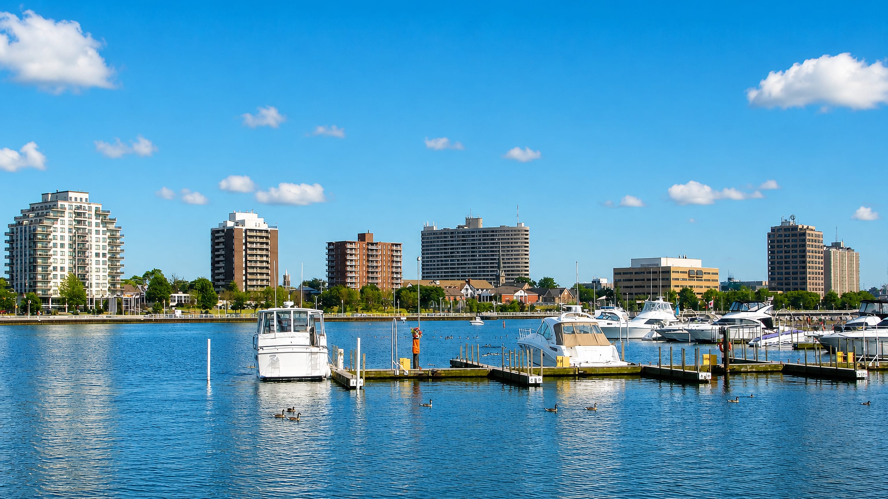 Sarnia, Ontario's waterfront skyline of apartment towers behind a marina of moored boats on calm water.