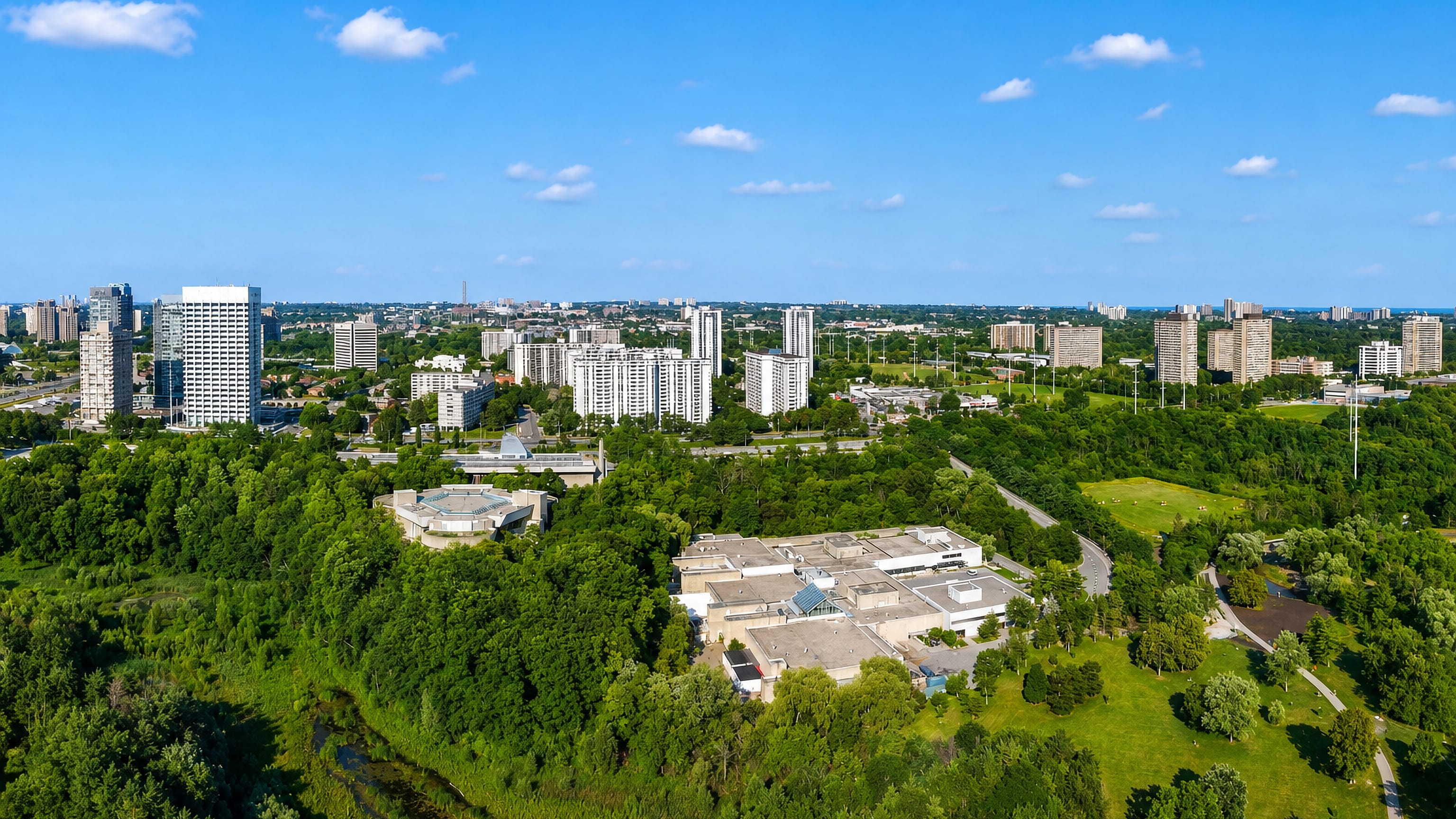 Aerial view over Flemingdon Park, Toronto, with apartment towers above the wooded Don Valley ravine and parkland.