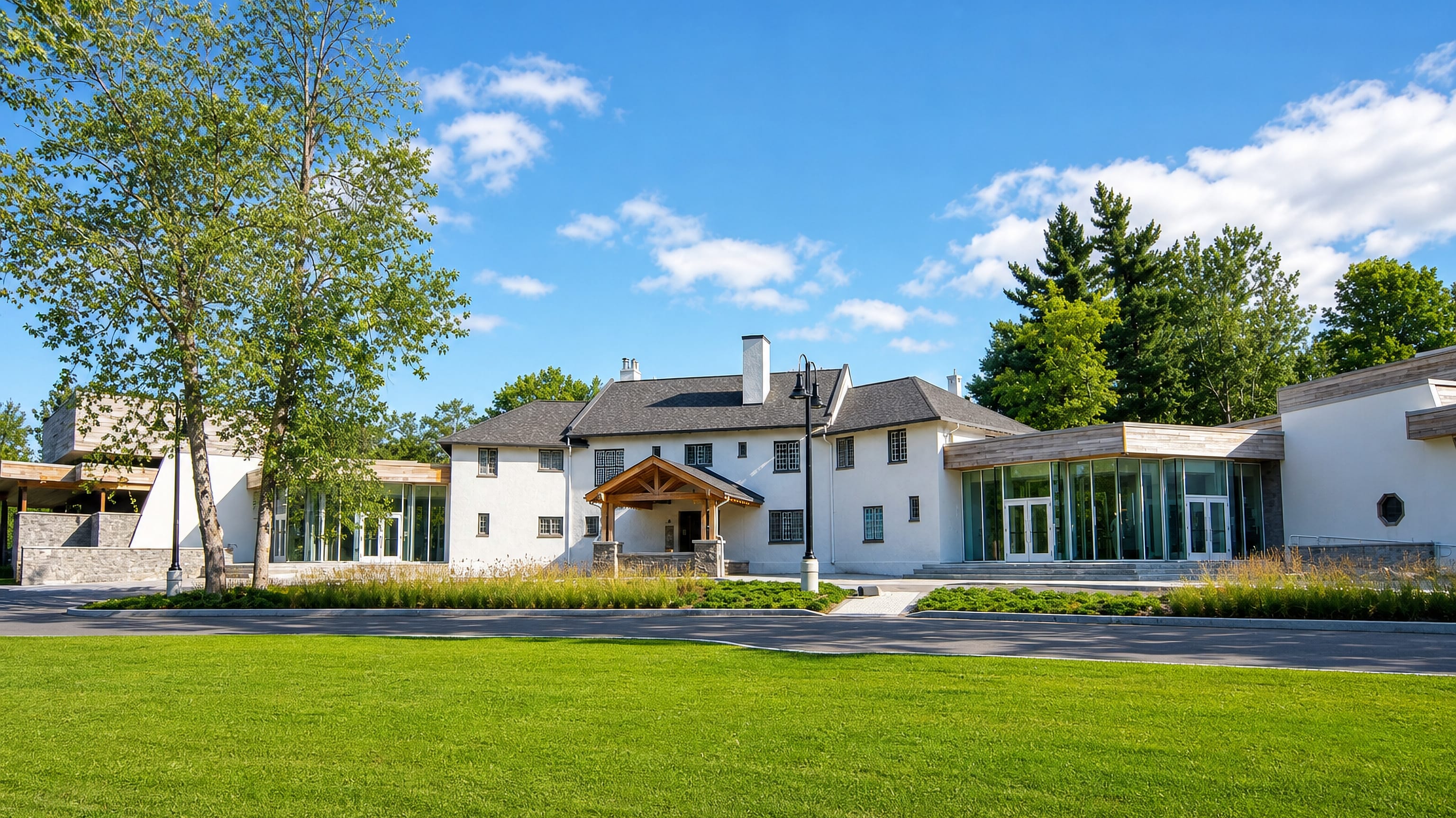 White heritage house with a modern glass pavilion and lawn at the Guild Inn Estate in Guildwood, Toronto.