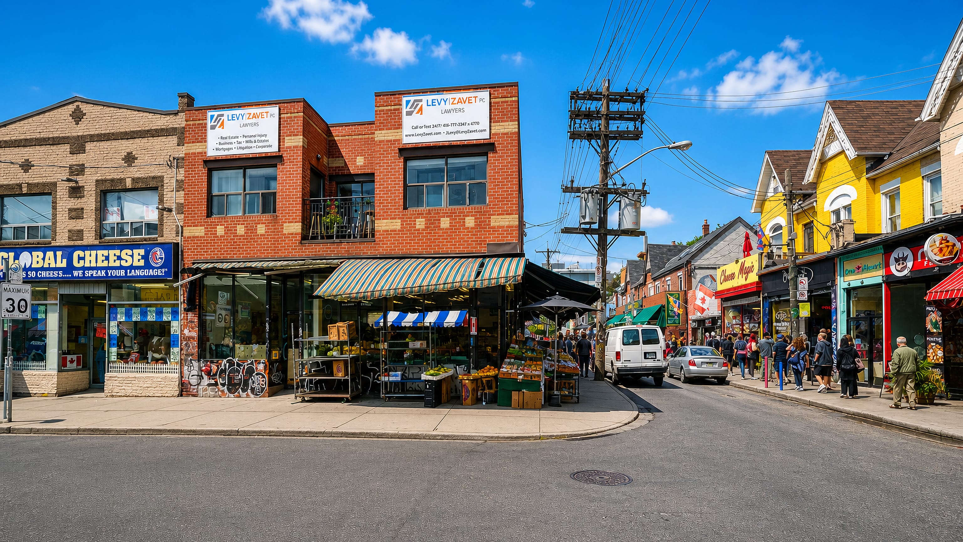 Colorful shop-lined market street with produce stalls and pedestrians in Toronto's Kensington Market.