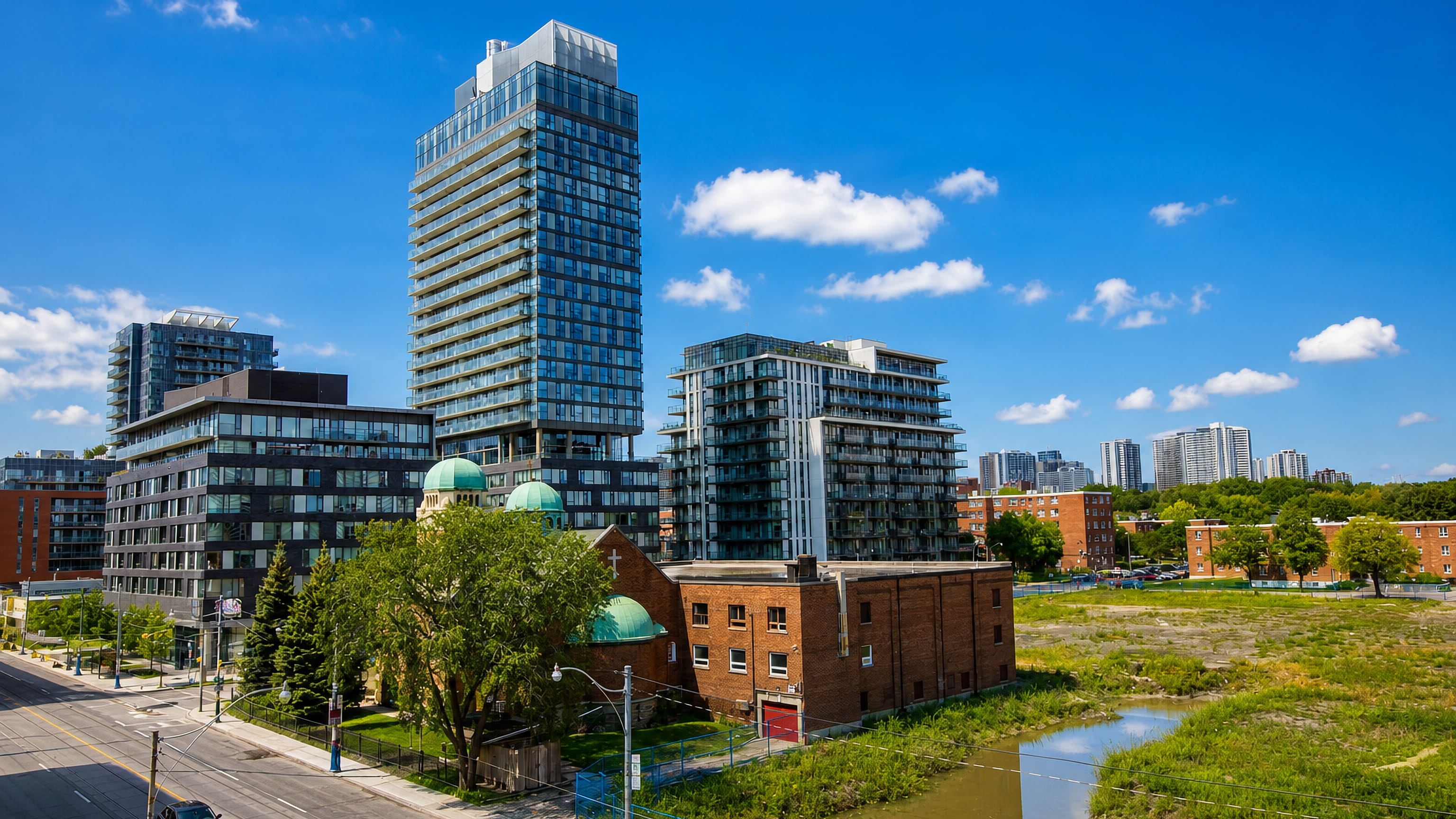 Glass condo towers rising above a domed brick church and vacant redevelopment land in Regent Park, Toronto.