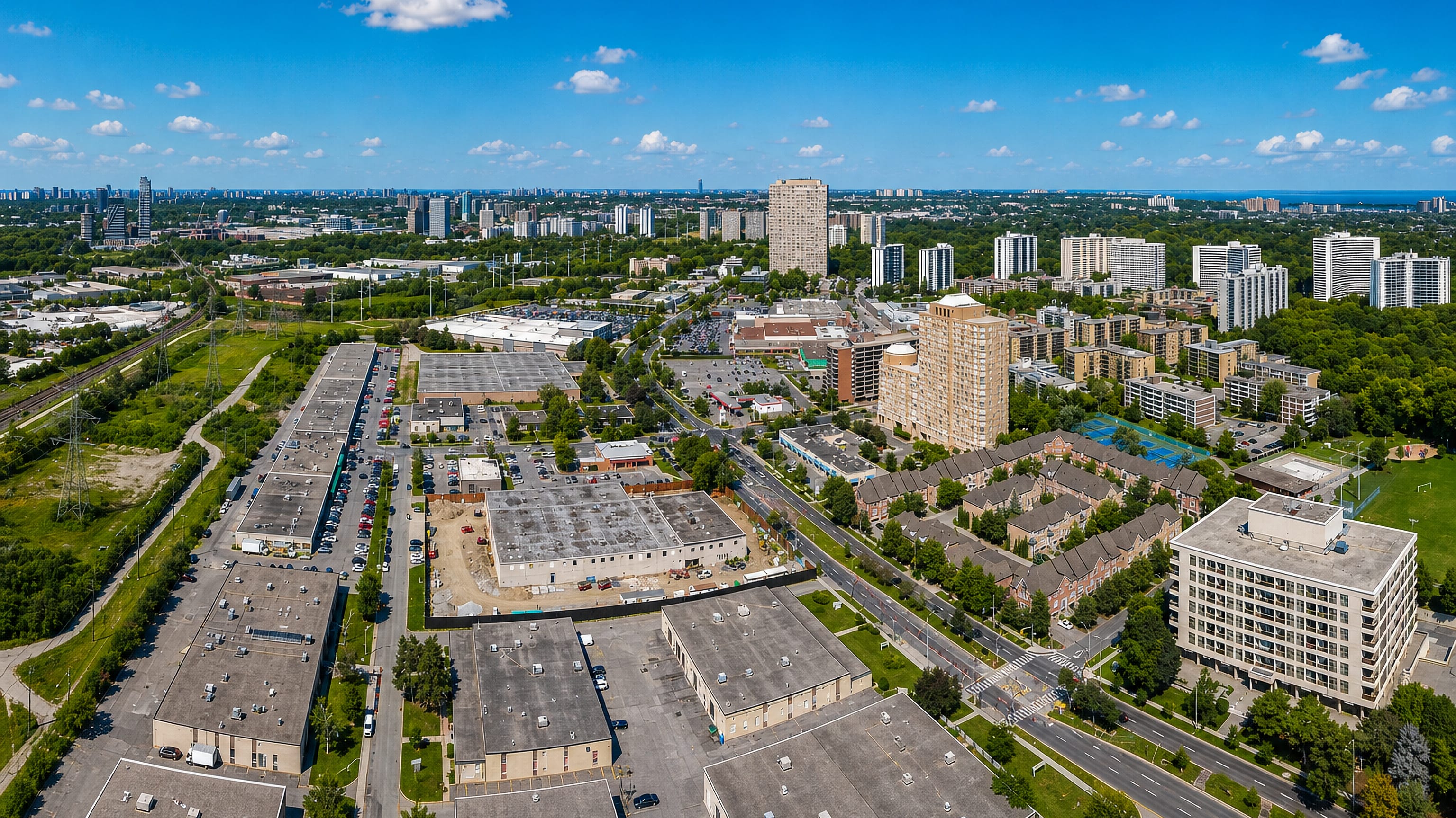 Aerial view of Thorncliffe Park in Toronto, low industrial buildings and apartment towers with the city skyline beyond.