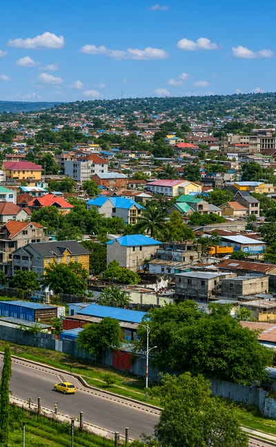 Aerial daytime view over the dense colorful-roofed residential neighborhoods of Lemba, Kinshasa, with green hills behind.