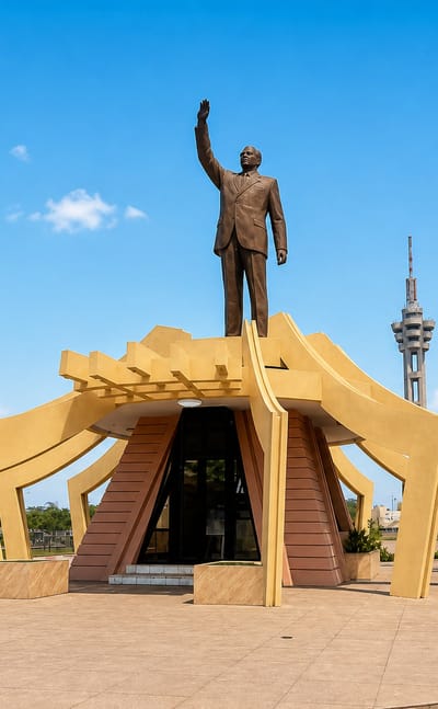 The golden Lumumba monument and the Limete telecommunications tower rising over a plaza in Limete, Kinshasa.