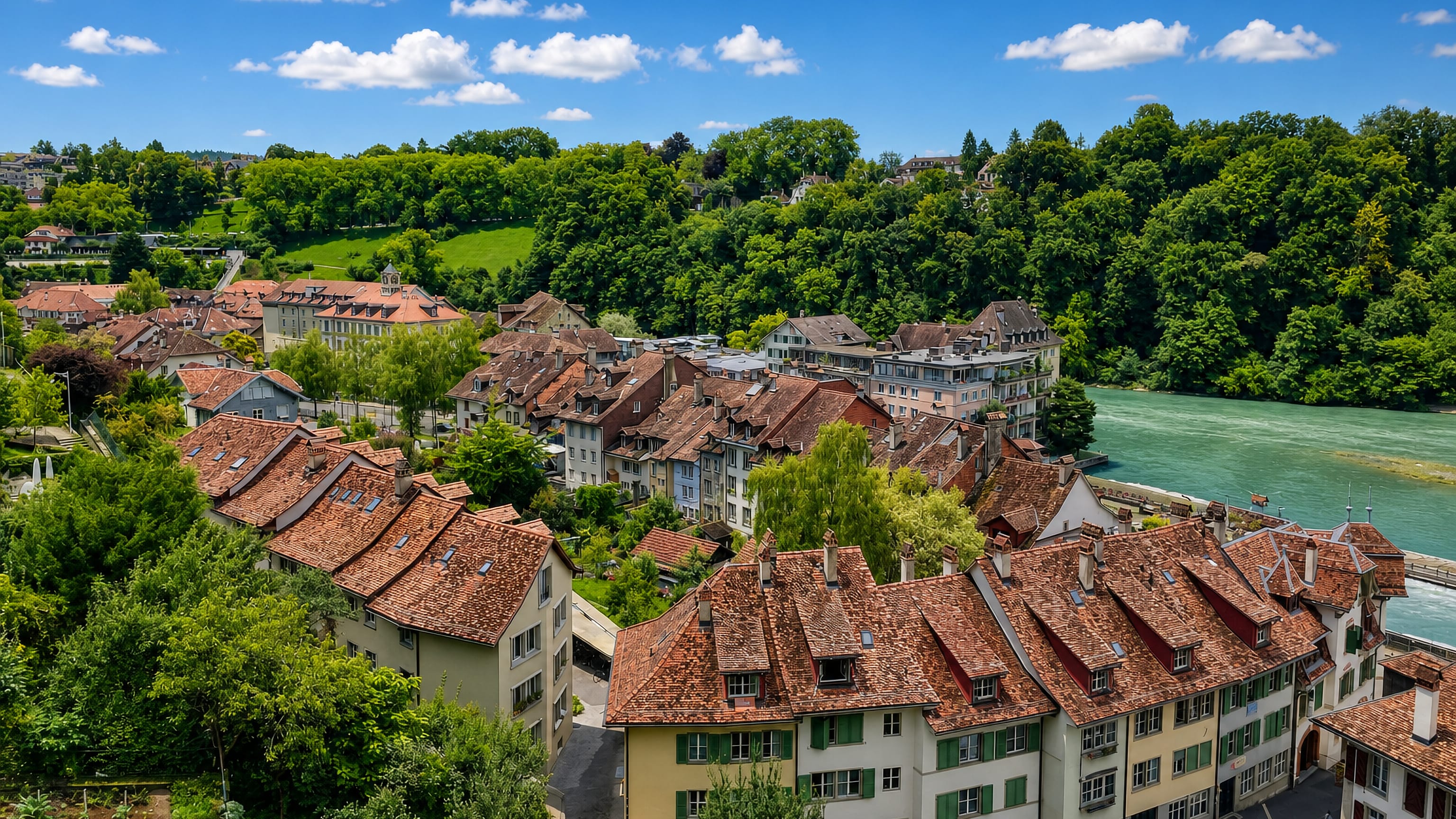 Tiled rooftops of Bern's Matte quarter along the turquoise Aare below wooded slopes.