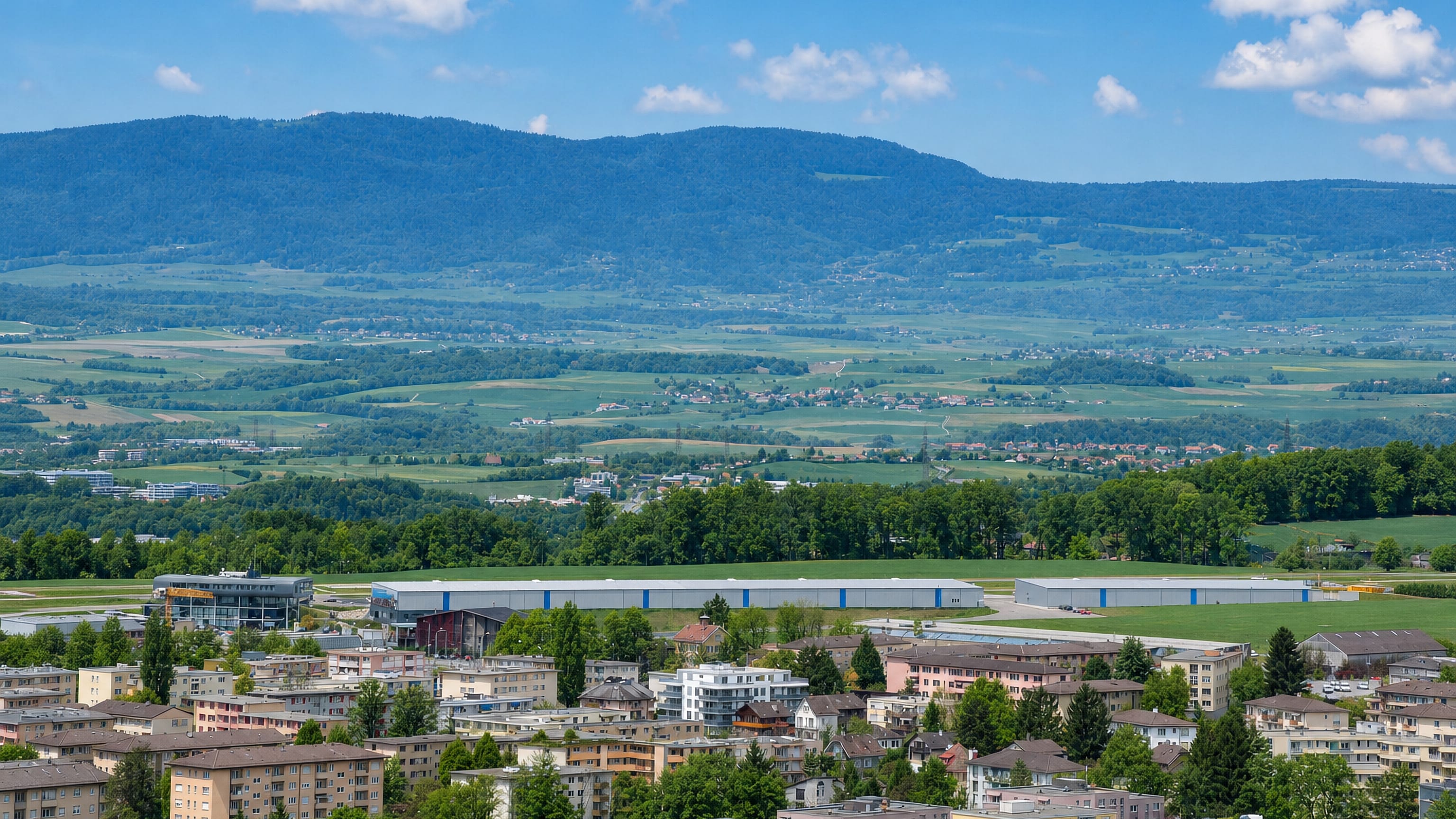 Apartment blocks above the Blecherette airfield in Lausanne, with the Jura ridge on the horizon.