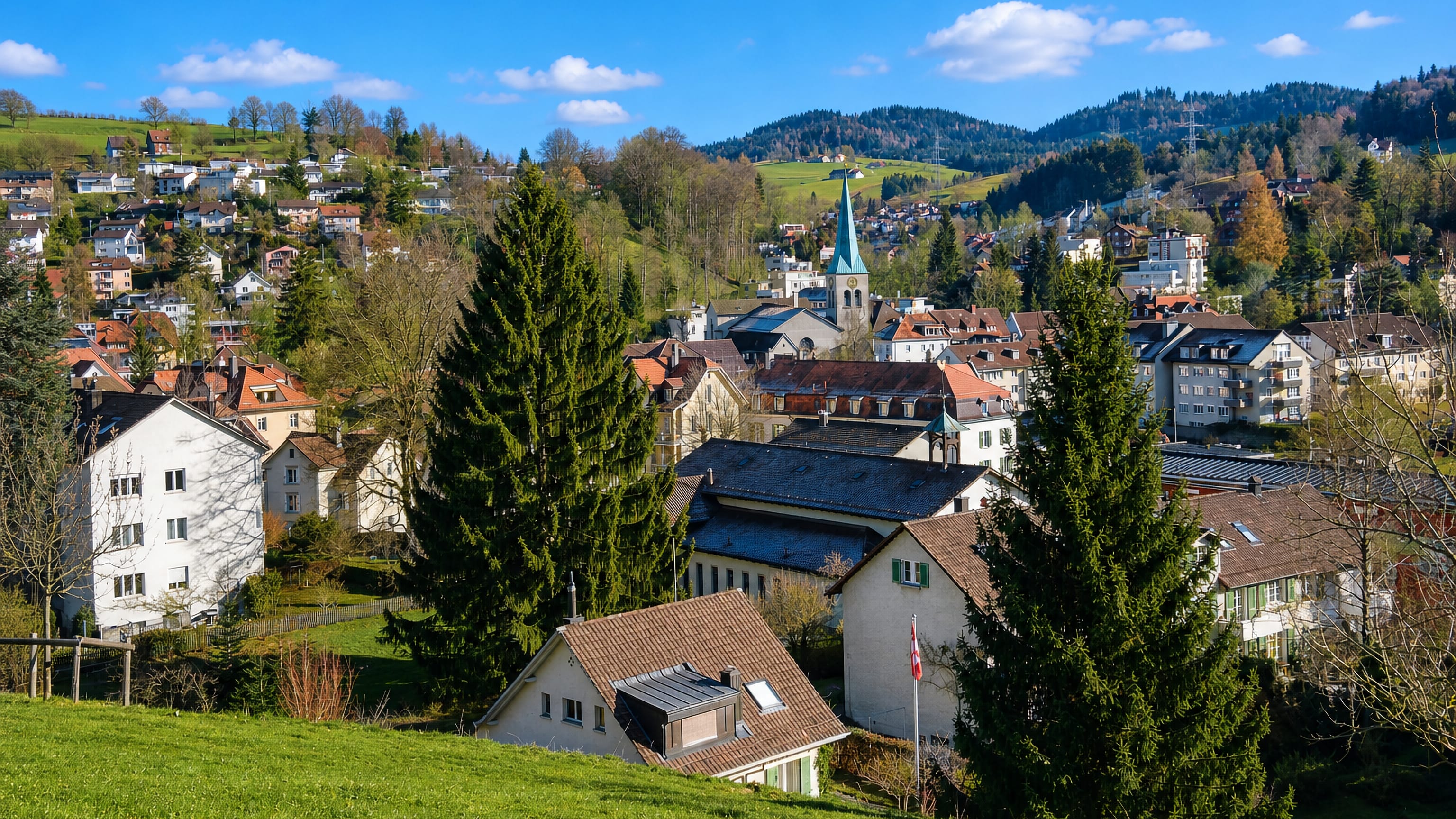Hillside houses and a church spire in the wooded valley of St. Georgen above St. Gallen, Switzerland.