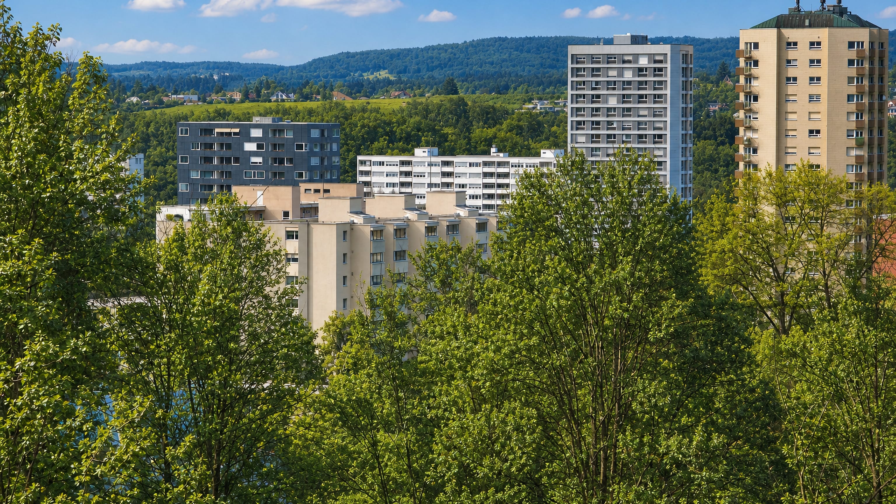 Modernist housing blocks and a tower rise above leafy treetops below wooded hills in Zurich Hirzenbach.