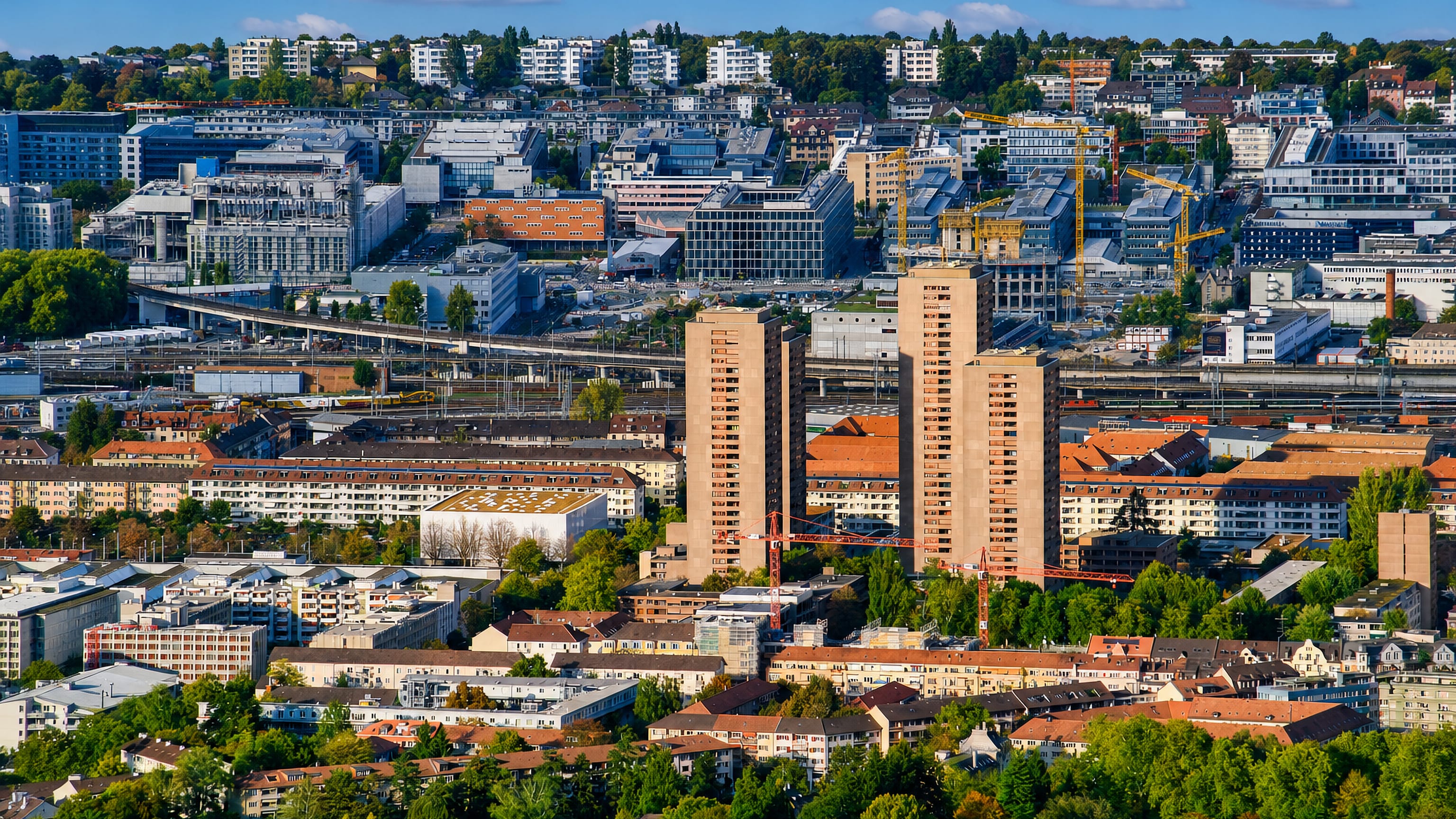 Aussersihl, Zürich Kreis 4, from above: brown high-rise towers, rail lines and construction cranes.