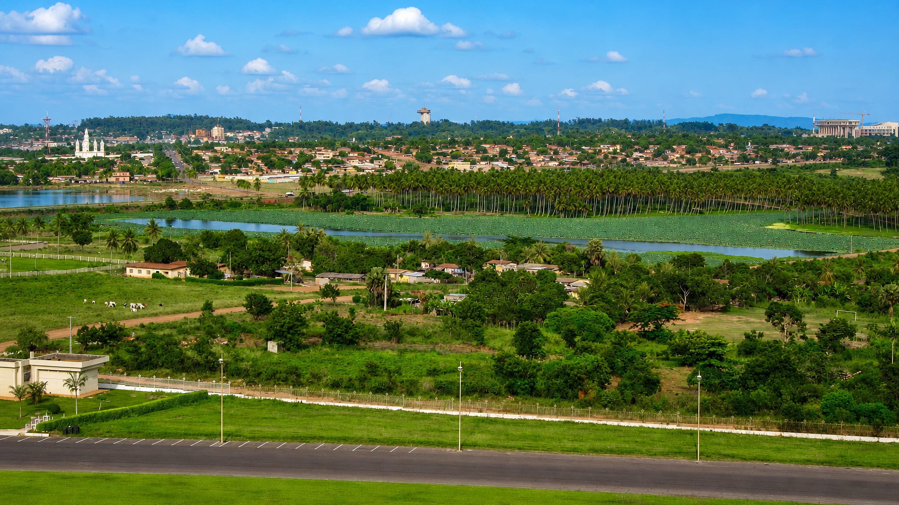 Yamoussoukro, Ivory Coast, green landscape with a lake and the distant basilica beyond palm groves.