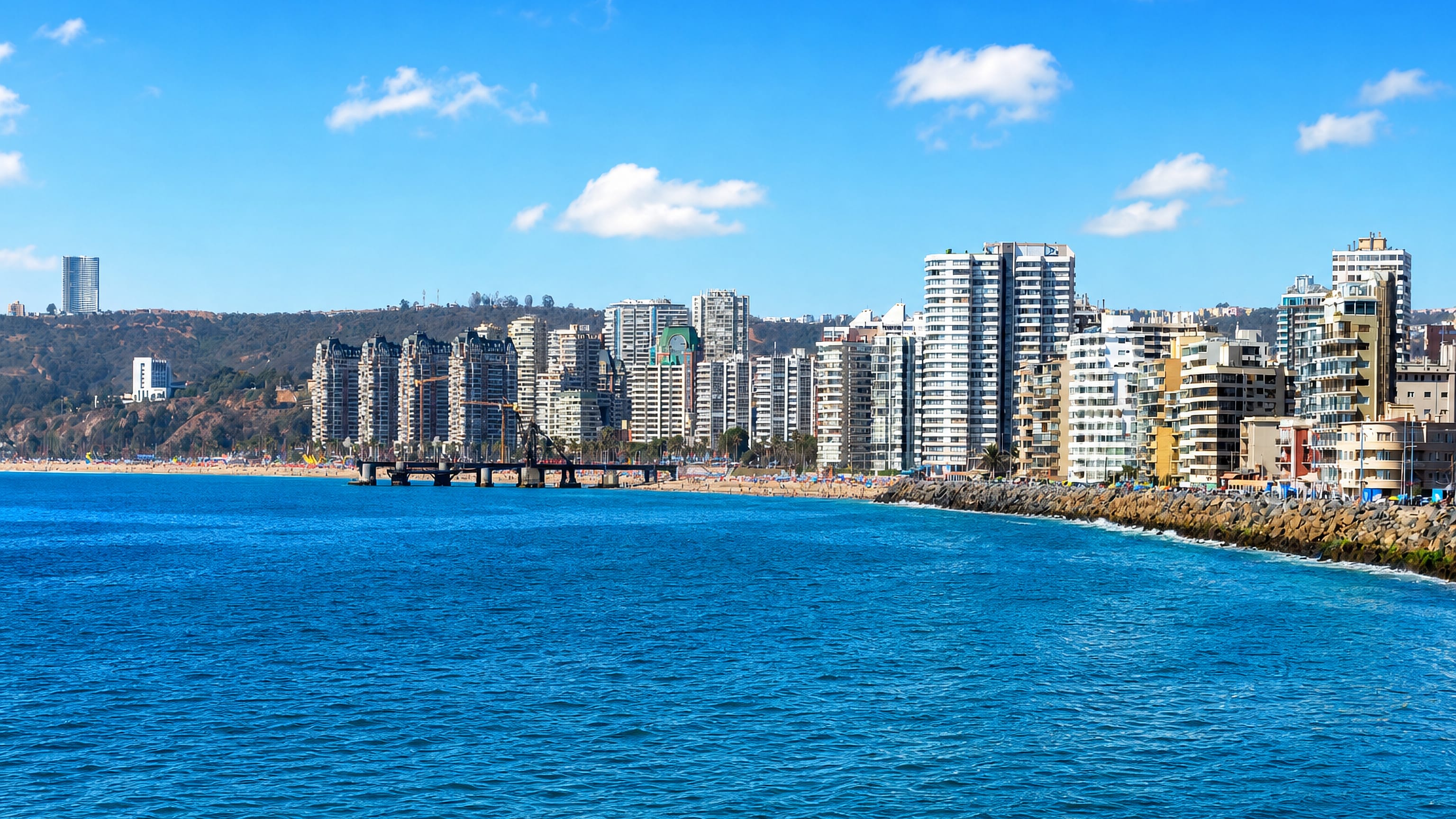 Viña del Mar's beachfront high-rise towers and Muelle Vergara pier along the sunlit Pacific shore.