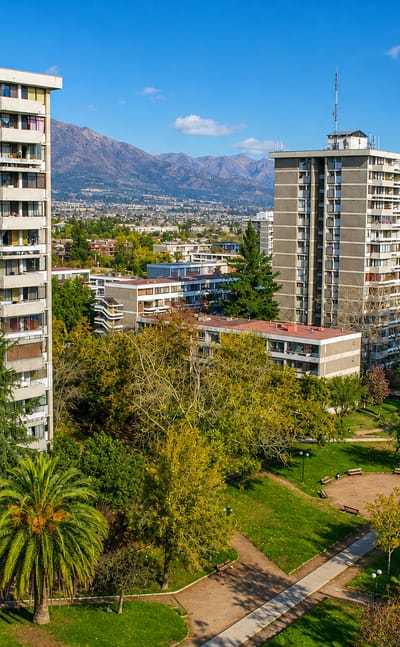 Modernist residential towers set in green parkland with the Andes rising behind, at Villa Presidente Frei in Santiago