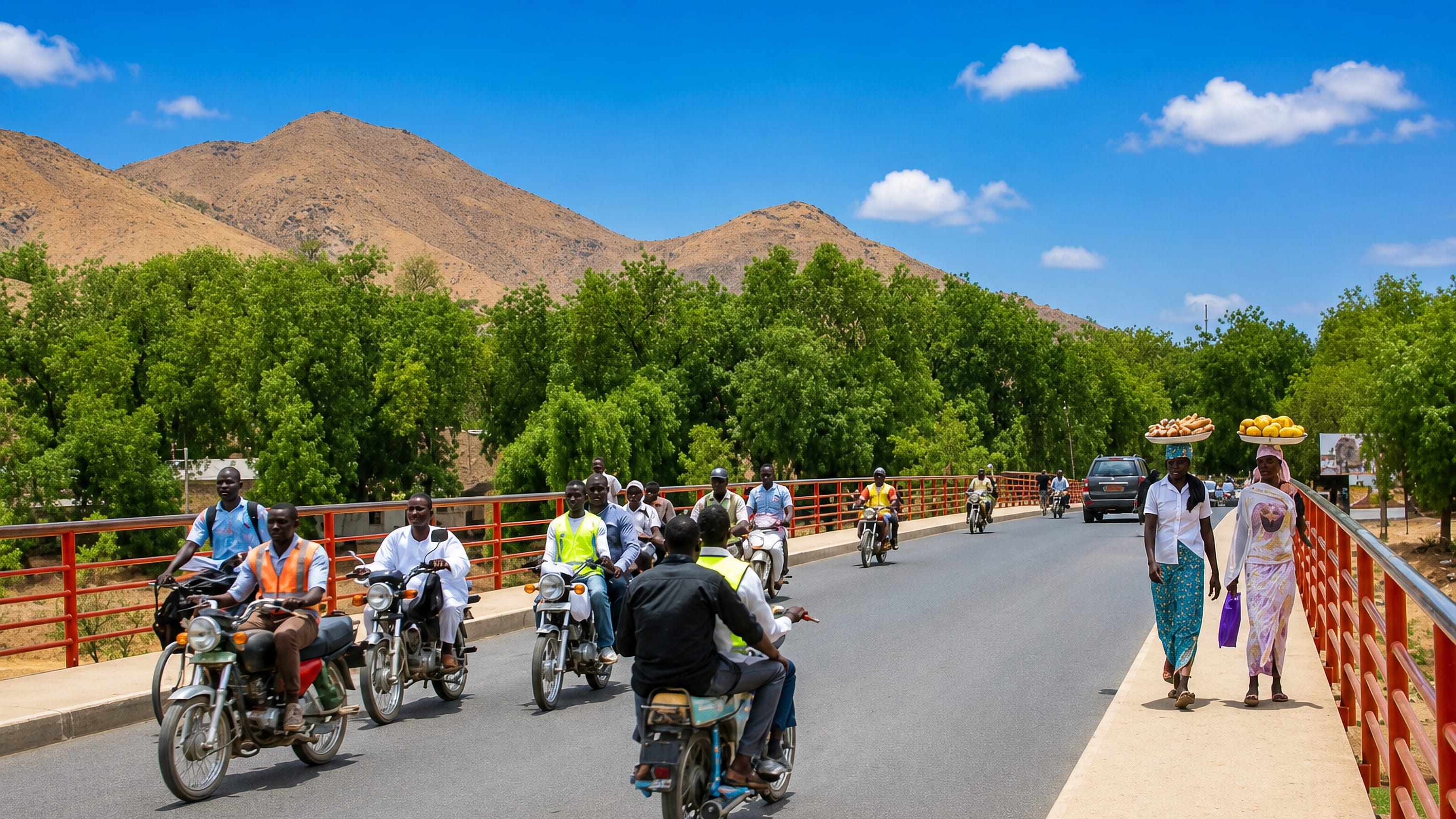 Motorcycle taxis and vendors crossing a red-railed bridge in Maroua, Cameroon, below dry foothills