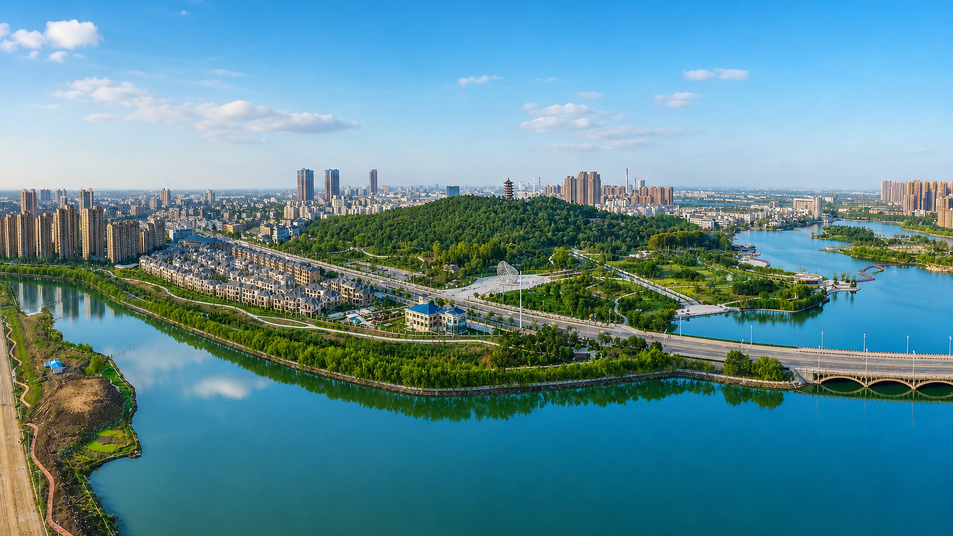 Aerial view of Bengbu, Anhui, with high-rises around a broad lake and a pagoda crowning a wooded hill.