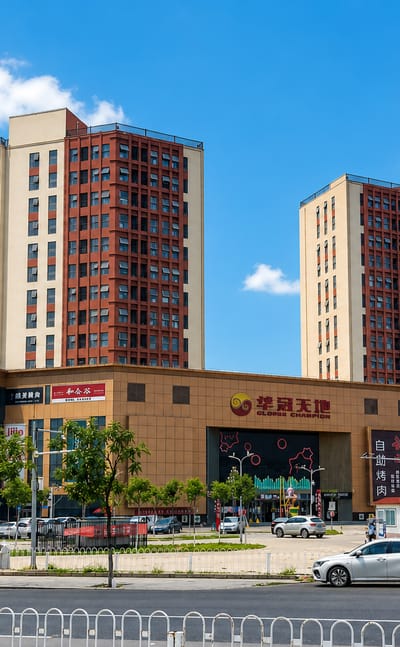 A modern shopping plaza and red-brick residential high-rises in Beijing's Fangshan District on a sunny day.
