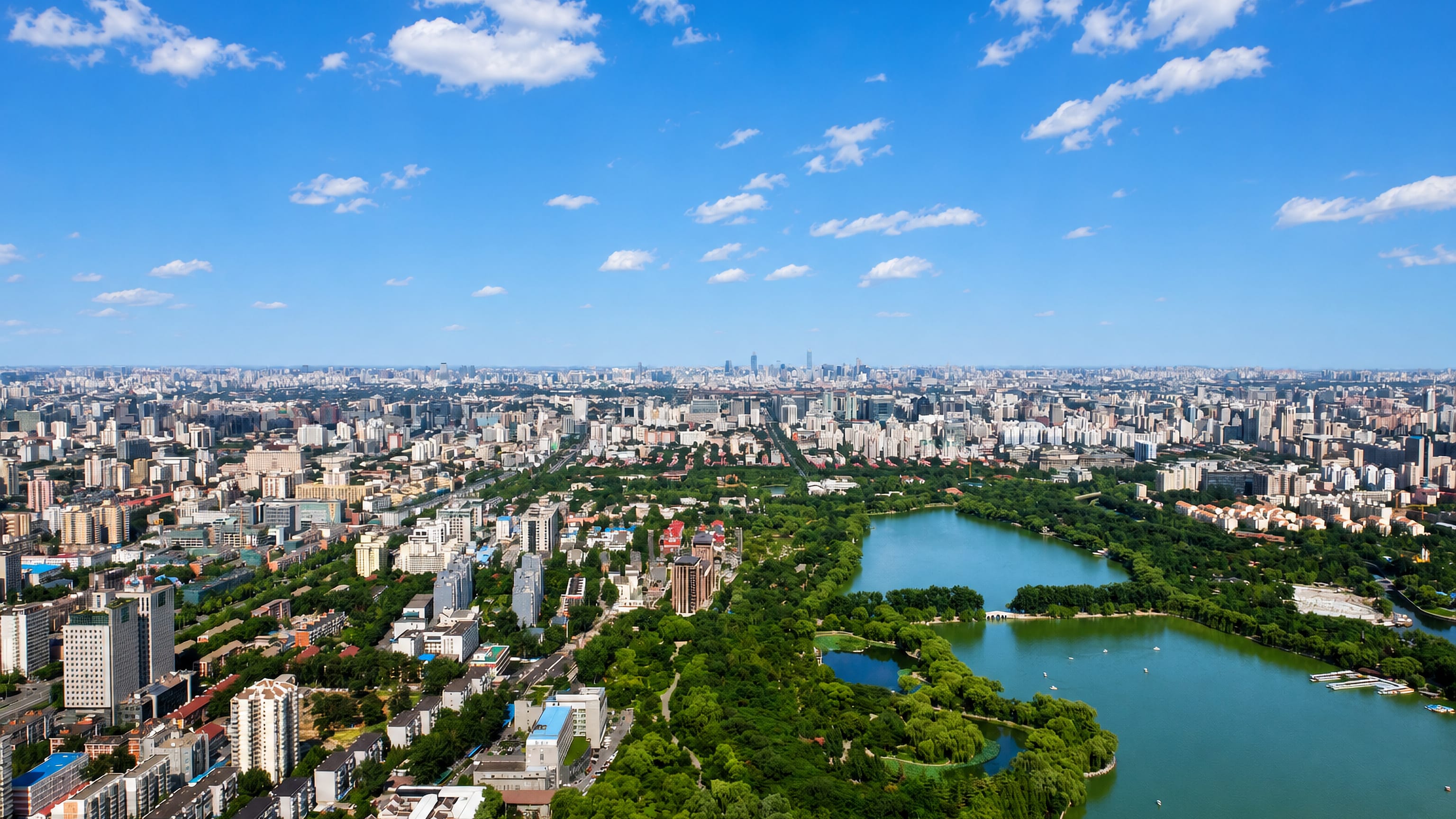 Aerial view across Haidian District, Beijing, a lake park in the foreground and the city skyline beyond