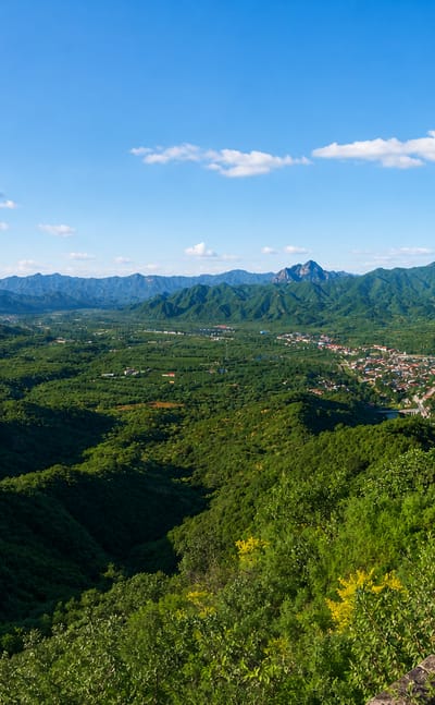 View from the Great Wall over forested mountains and a valley town in Huairou District, Beijing