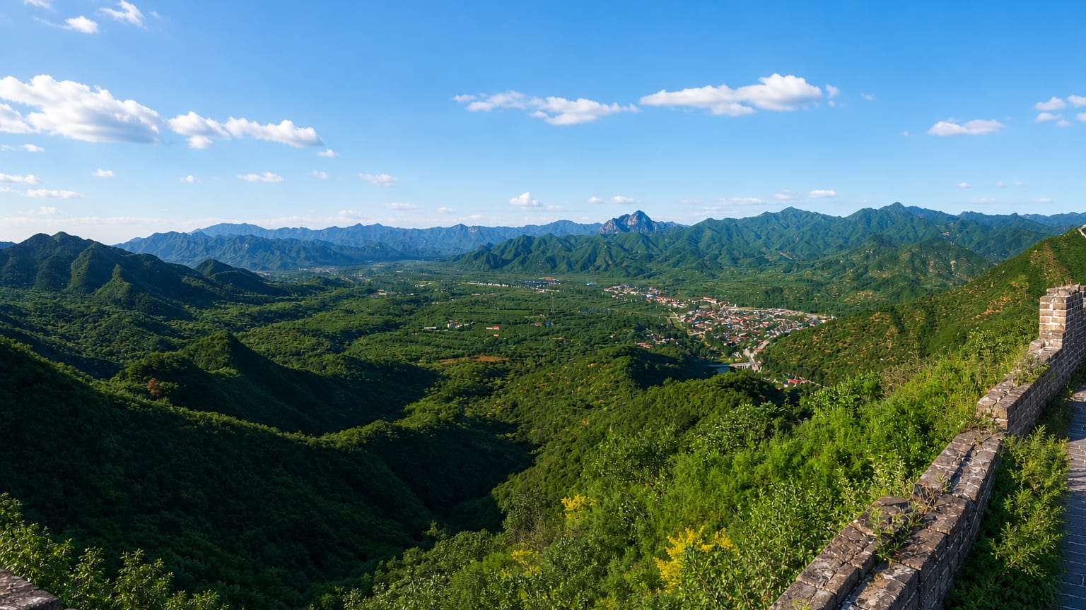 View from the Great Wall over forested mountains and a valley town in Huairou District, Beijing