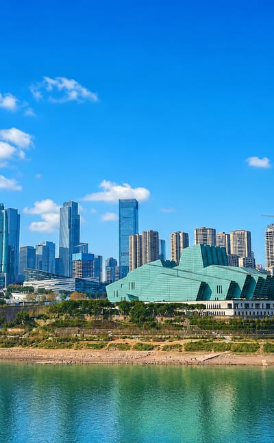 Liangjiang New Area skyline across the Yangtze in Chongqing, with the green-glass Grand Theatre and high-rise towers under a clear sky