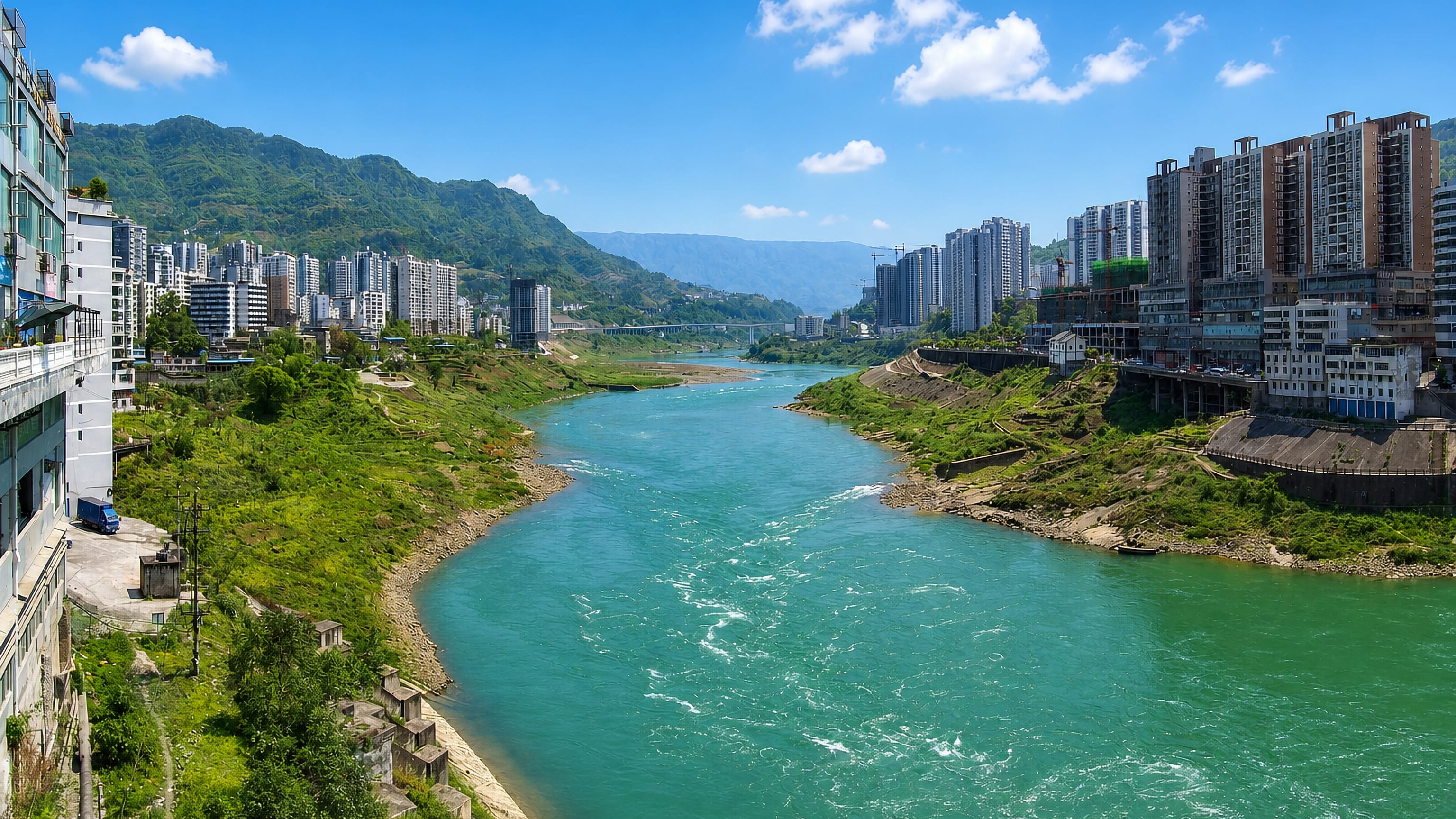 High-rise blocks lining the turquoise Wujiang river between steep green mountains in Wulong District, Chongqing.
