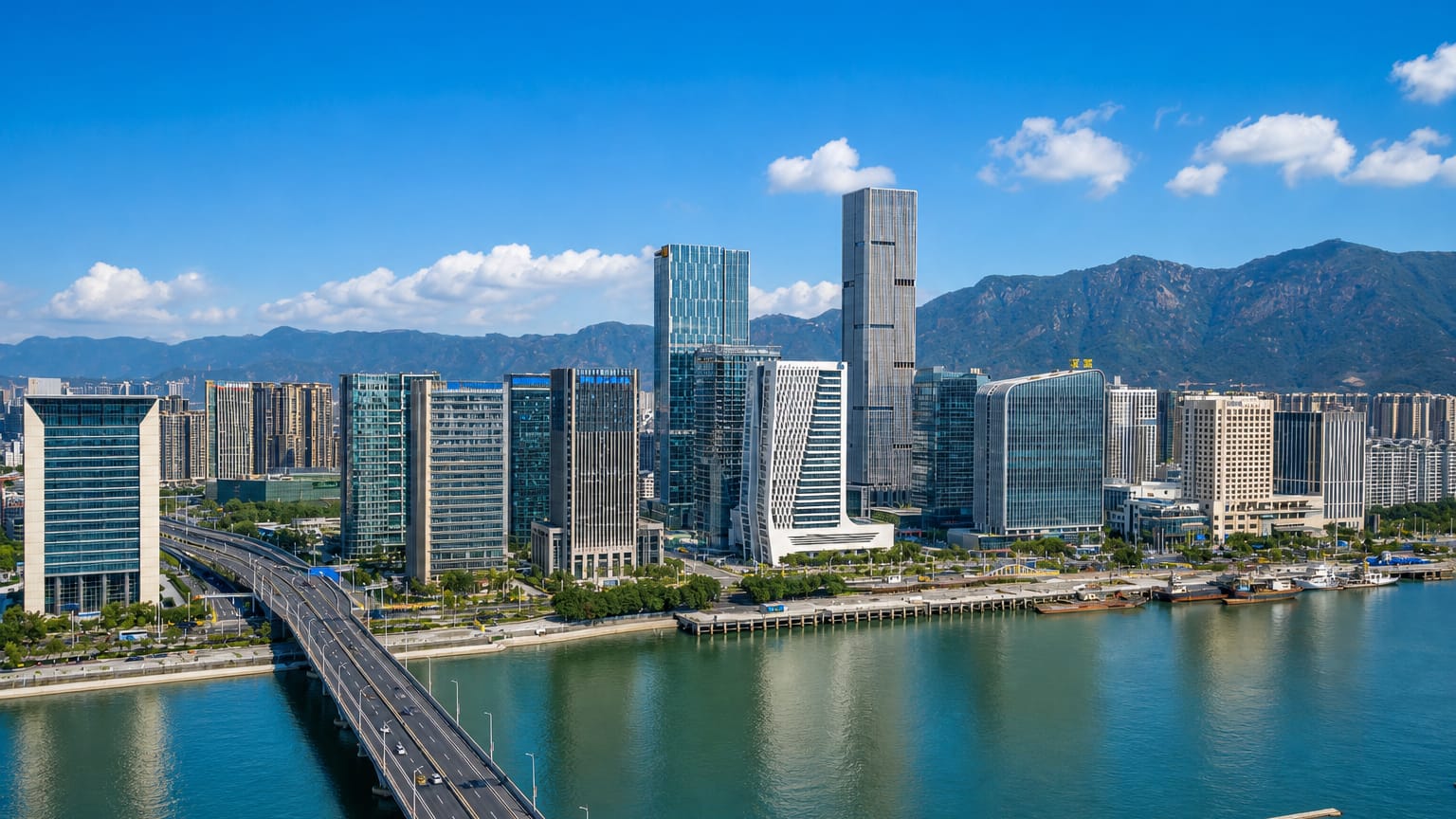 Fuzhou's riverside business district with a bridge over the Min River and mountains behind.